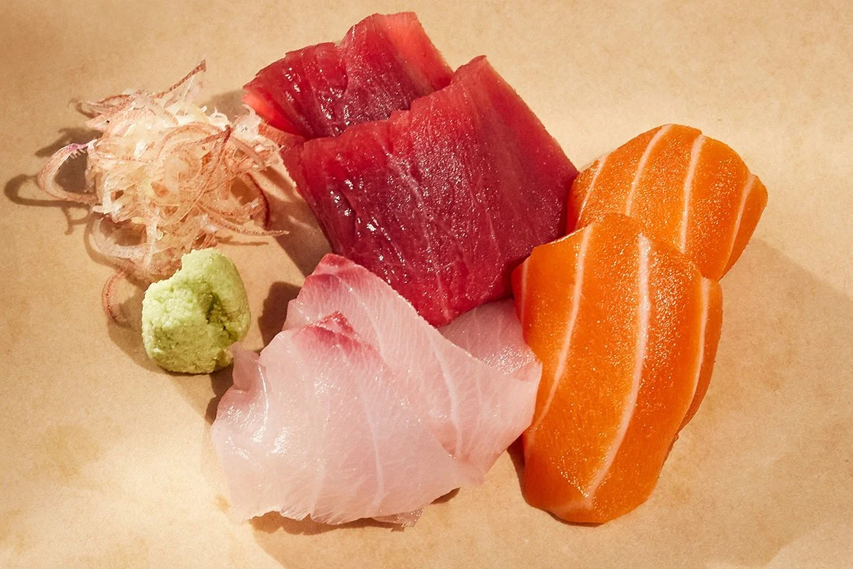Assorted dry aged sashimi including slices of salmon, tuna, yellowtail, garnished with wasabi and ginger.