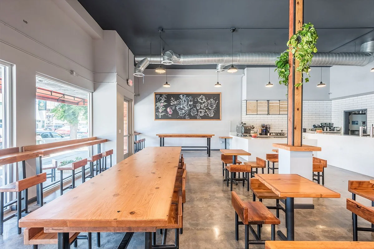 Image of the Uoichiba Sherman Oaks space with wooden tables and chairs, large windows, chalkboard art on the wall, and a visible coffee bar area.