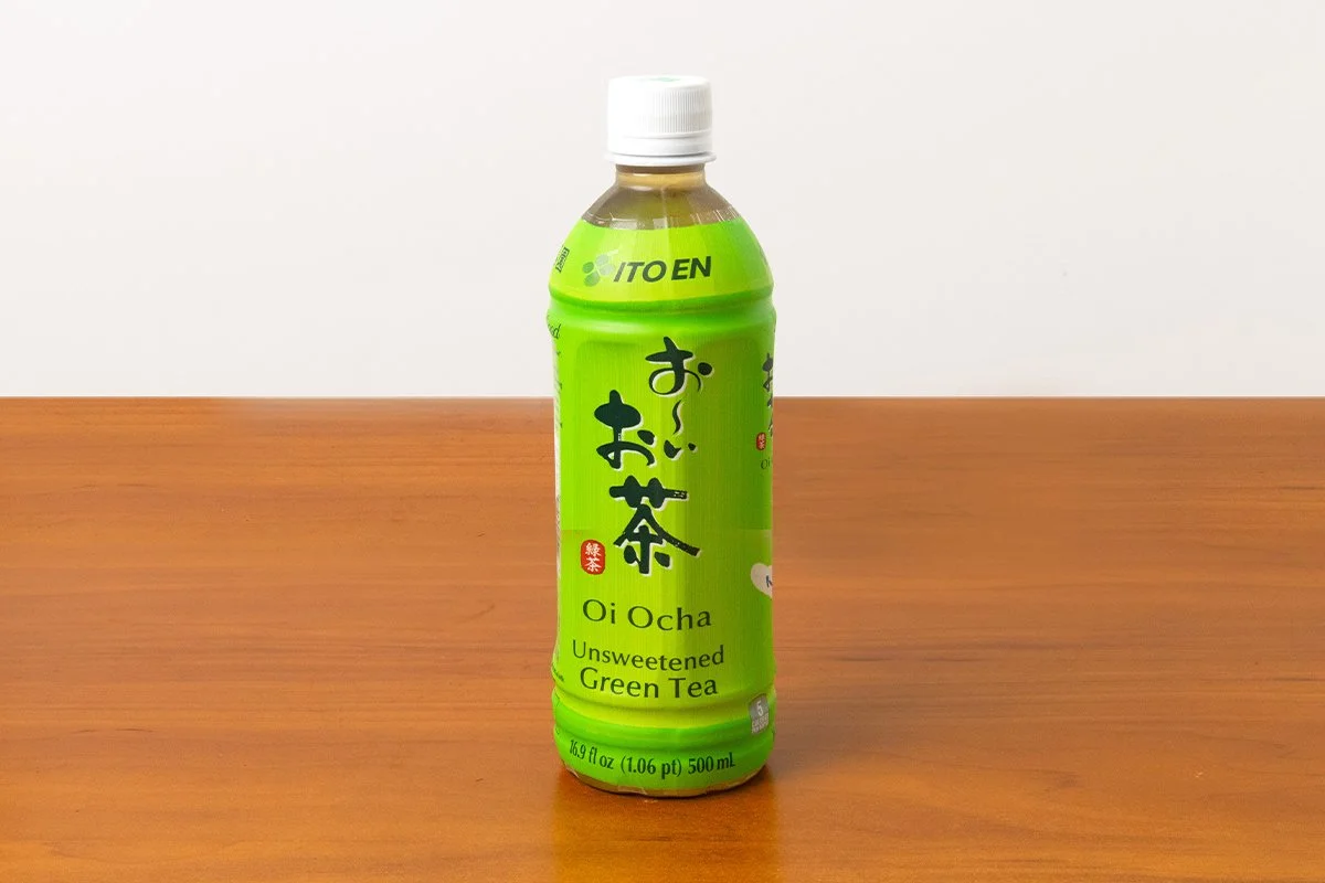 A bottle of Ito En Oi Ocha Unsweetened Green Tea placed on a wooden surface.