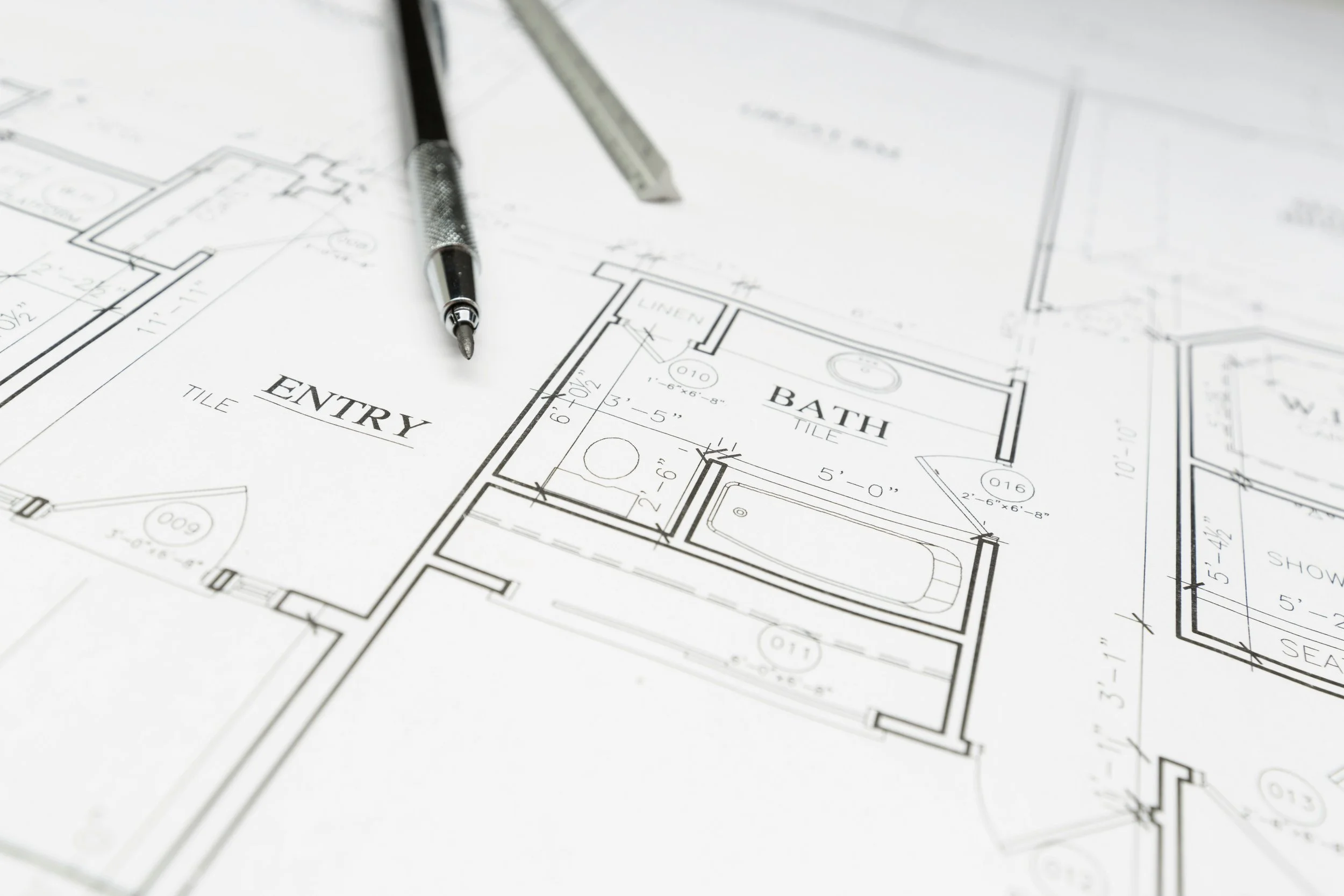 Architectural blueprint with two pens resting on top of it.