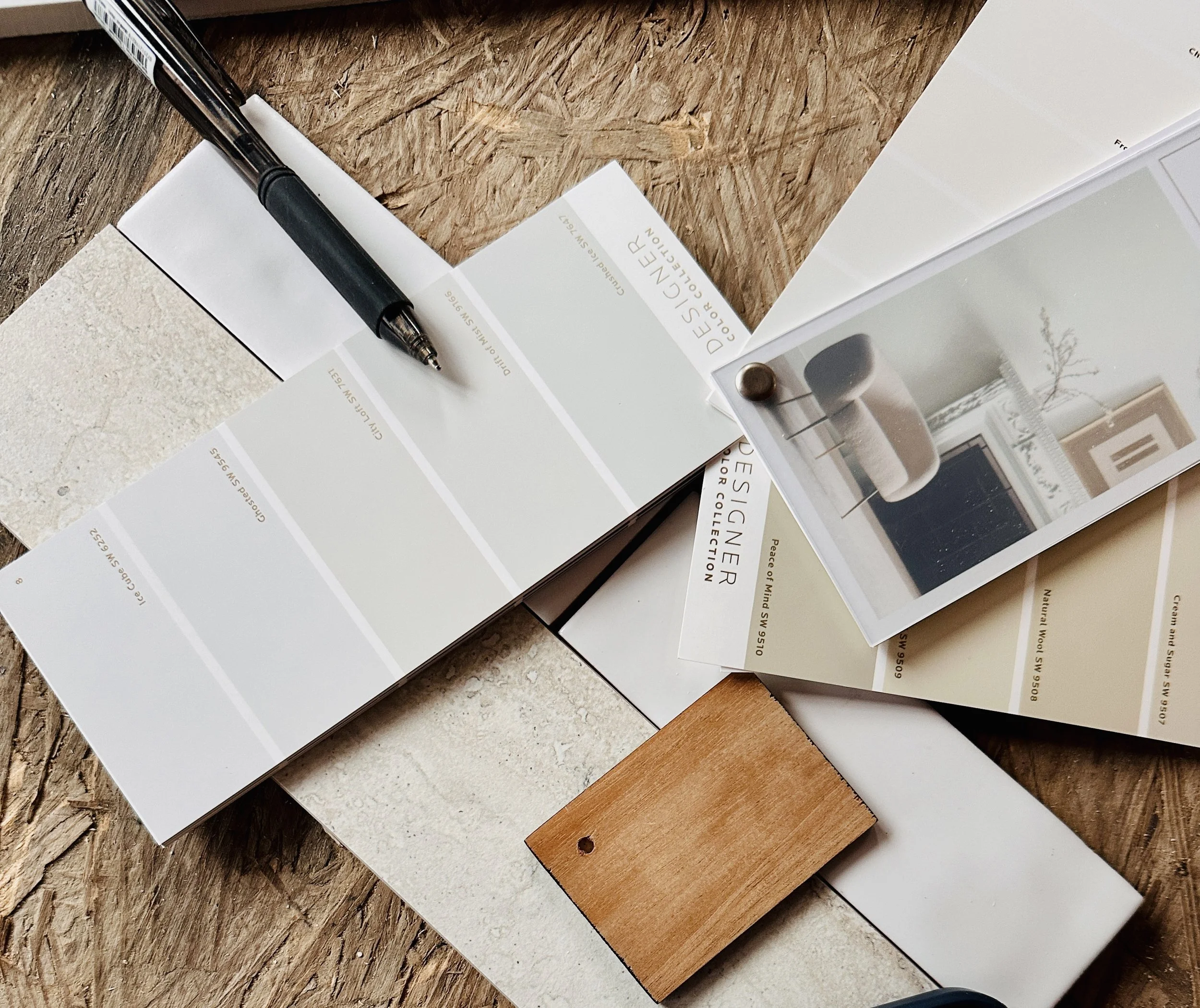 Samples of different building and interior finishing materials, including paint, fabric, wood, and tiles, laid out on a wooden surface.