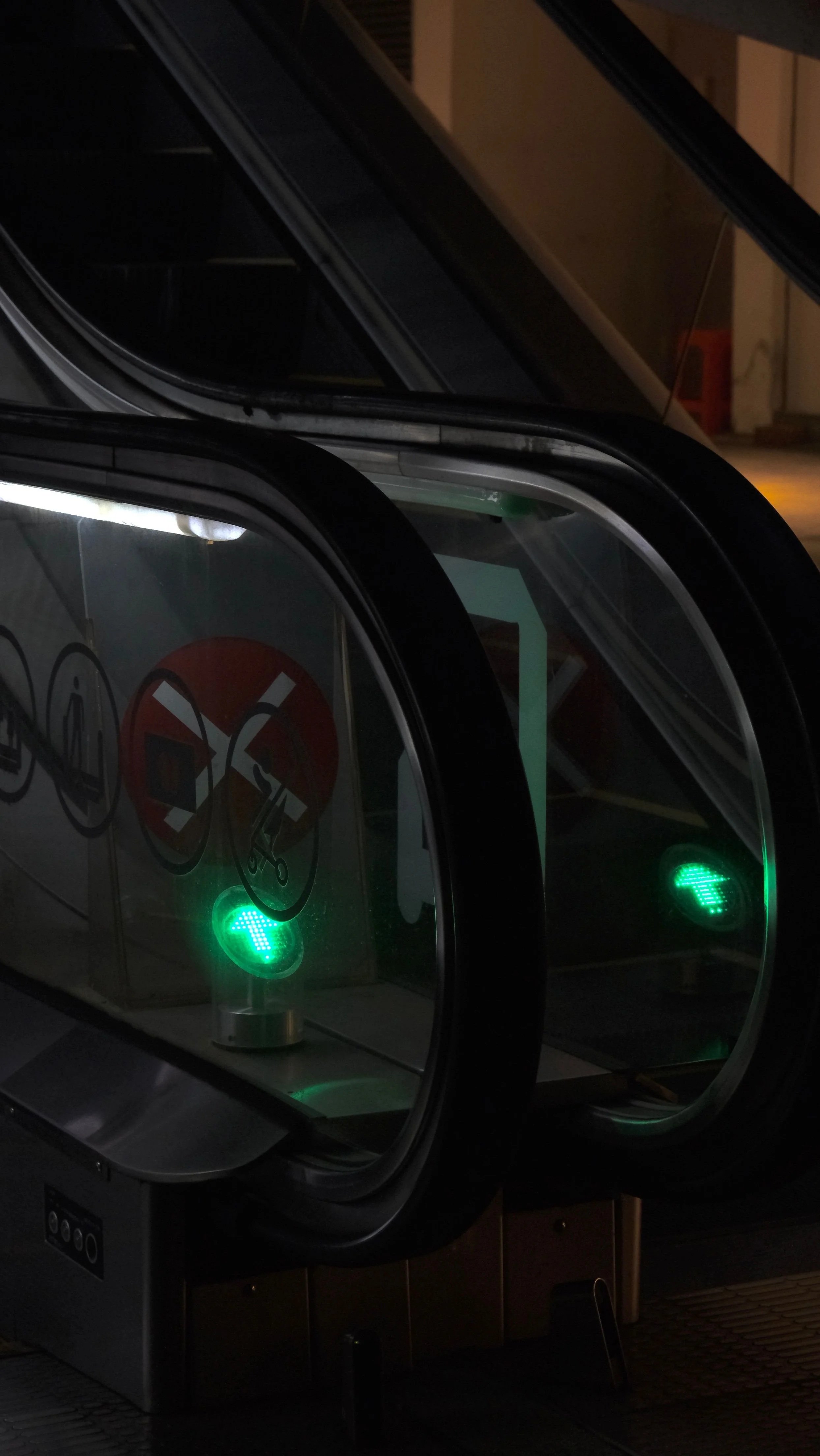 an escalator within a dark space, with a bright green arrow illuminated