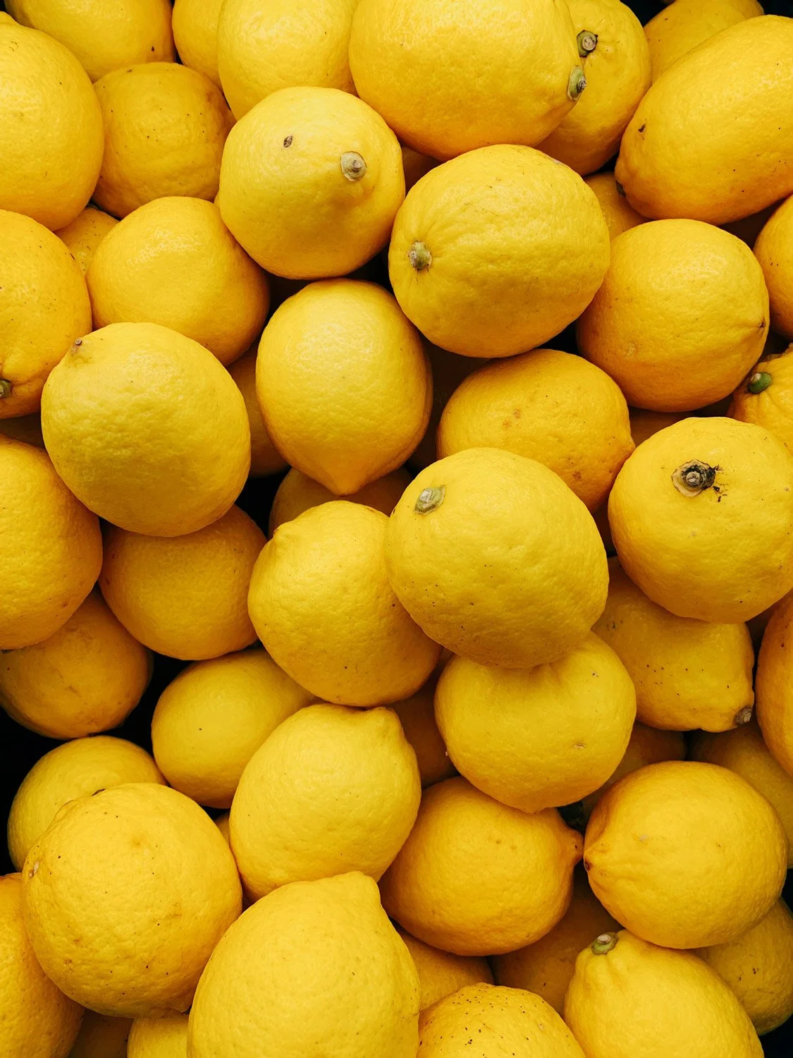 A pile of bright yellow lemons with textured skin representing life after trauma and grief with therapy.