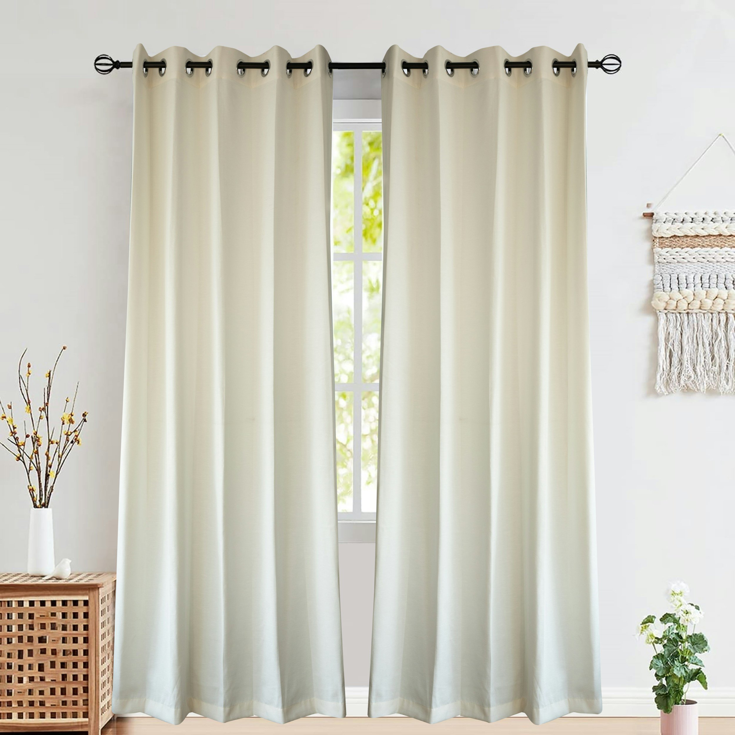 Cream-colored curtains hanging in front of a window with greenery outside, next to a basket and potted plant in a well-lit room.