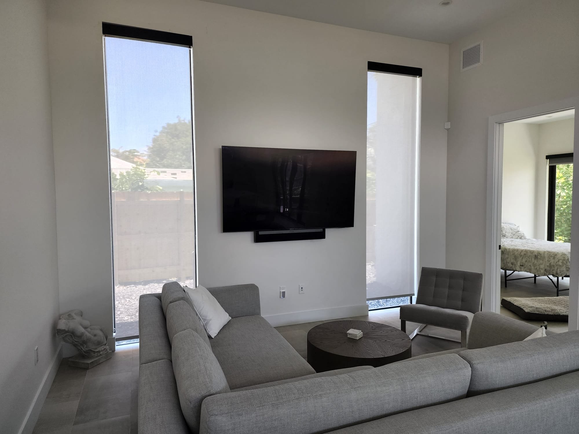Living room with two tall windows with roller screen shades for glare reduction, heat rejection, and day time privacy.