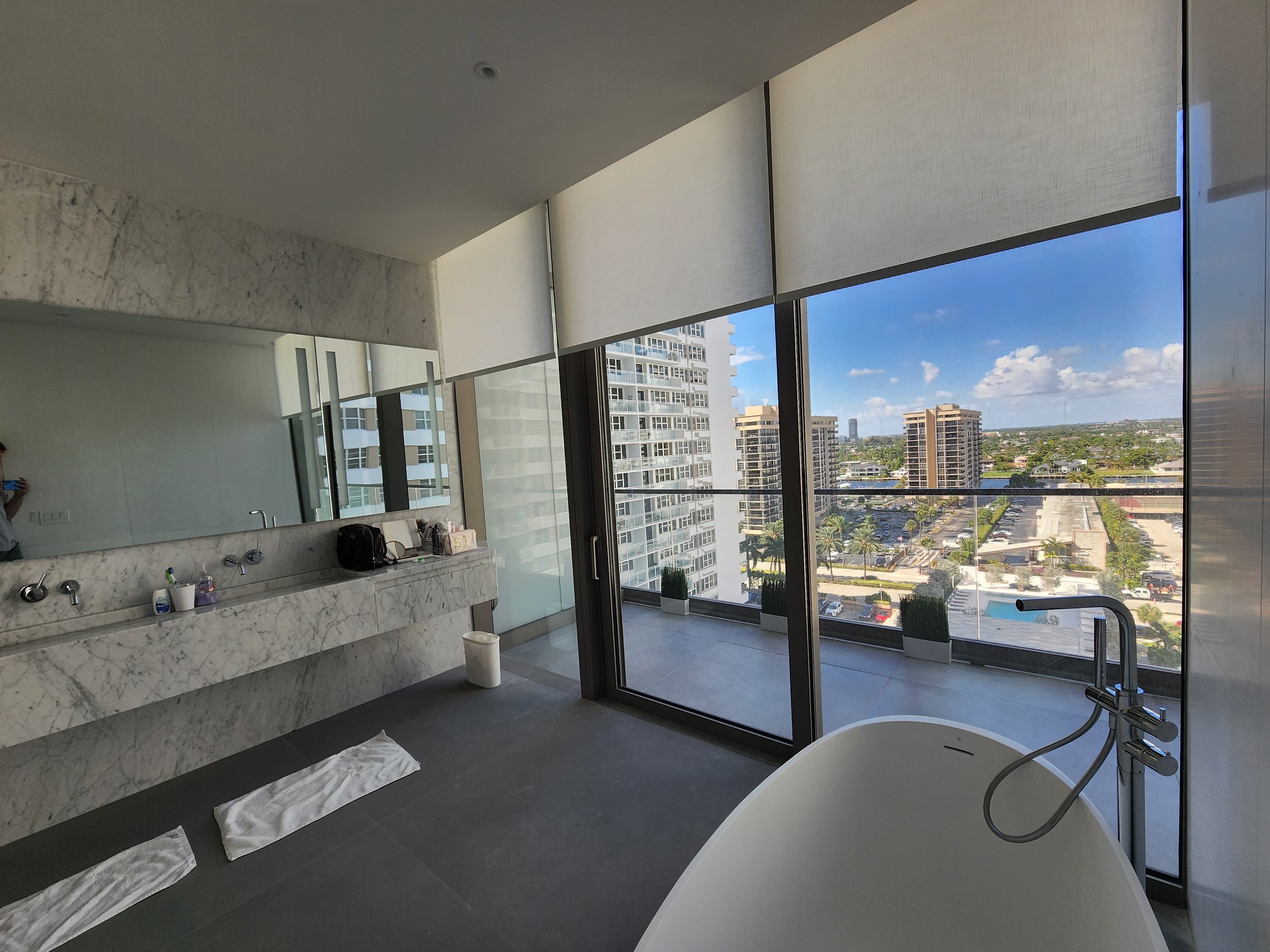 Modern bathroom motorized light filtering roller shades for privacy and light control.