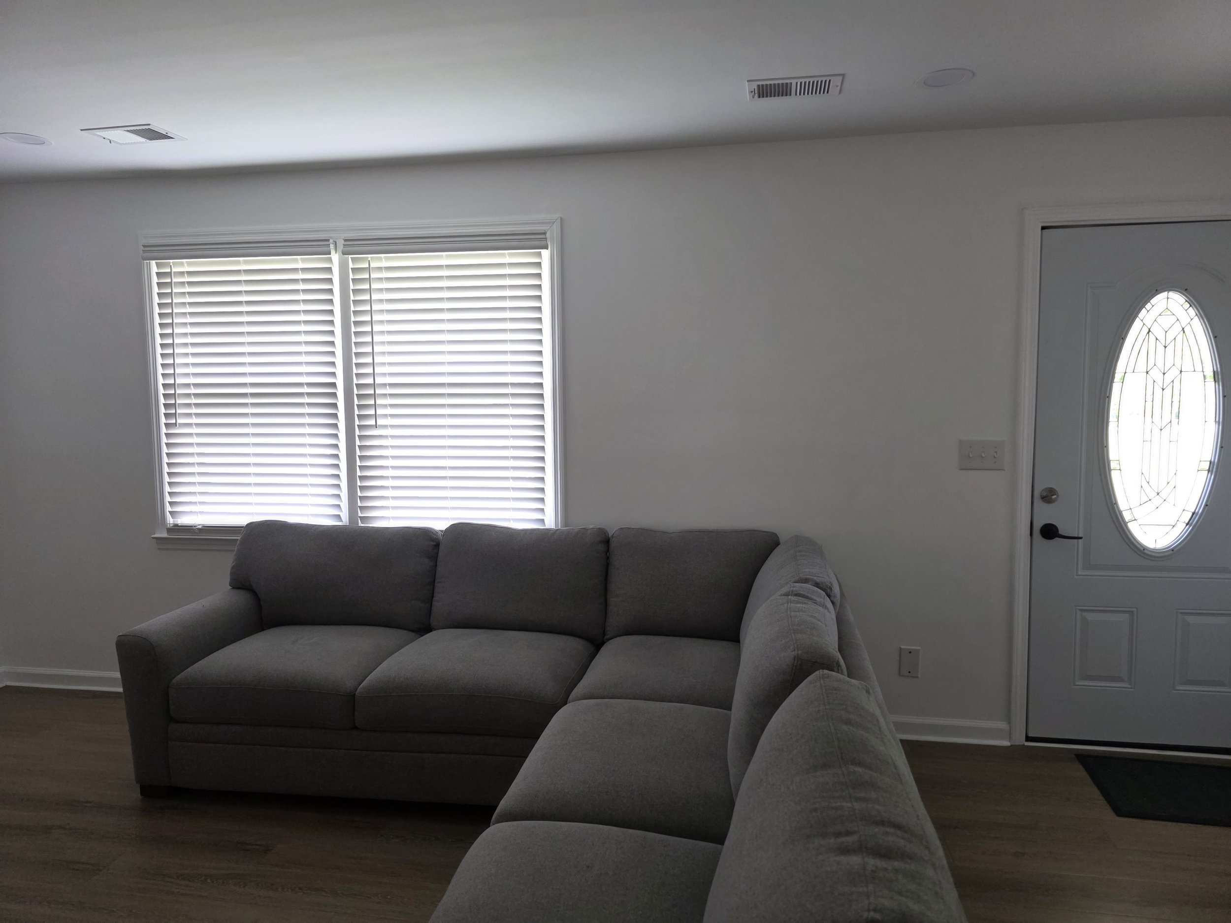 Living room with white horizontal faux wood blinds for light control, privacy, and heat rejection.