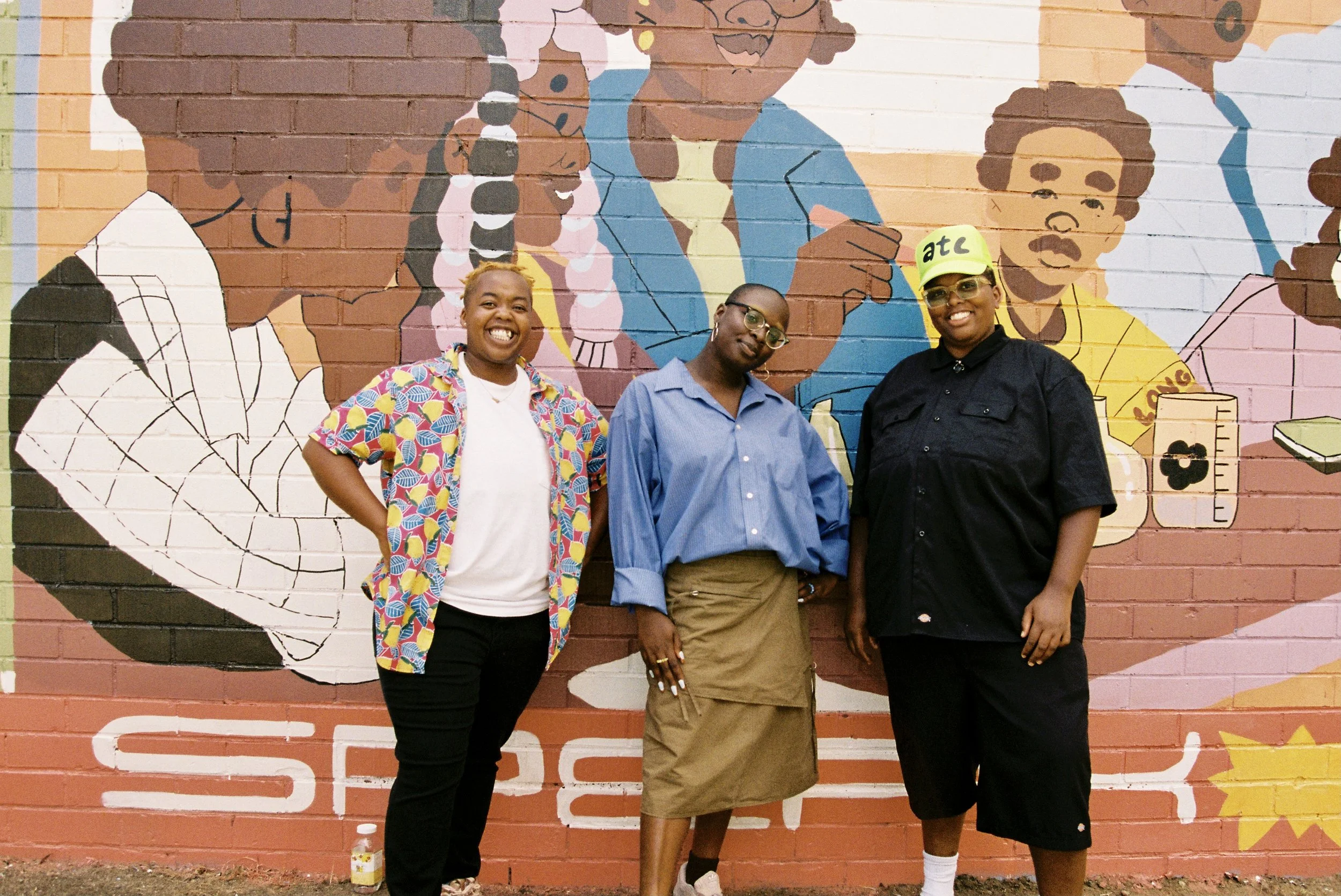 Pia, Sage, and Cienna pose in front of the Speak and We Will Listen Mural at Crawford Long Middle School in East Point, Georgia.
