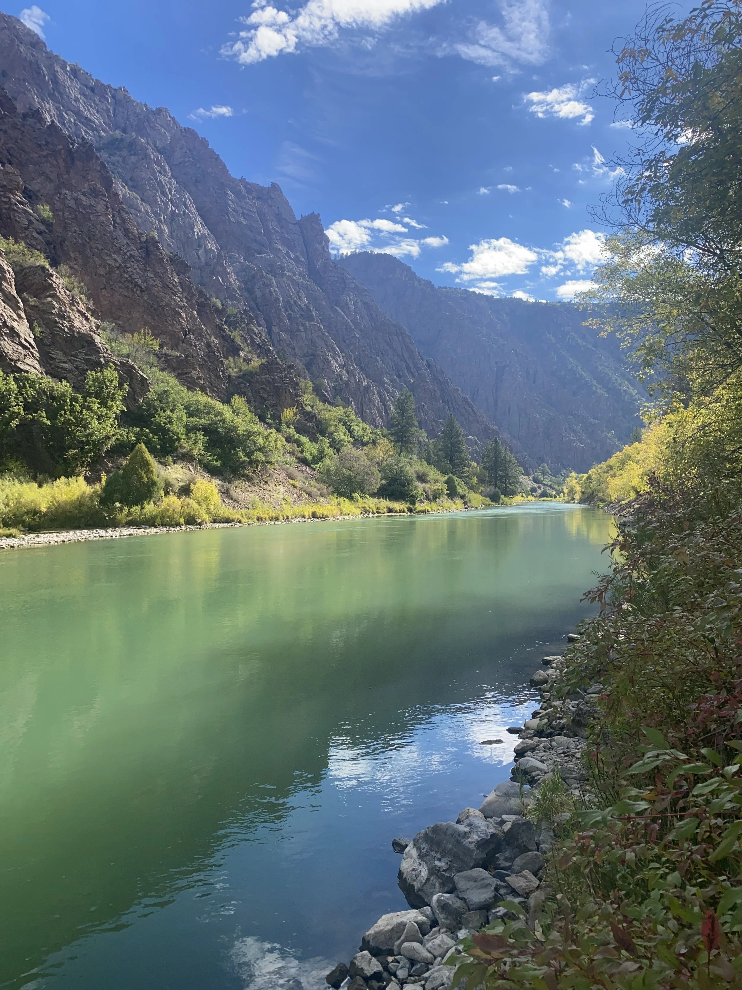Turquoise river winding through a rugged mountain gorge beneath a bright blue sky