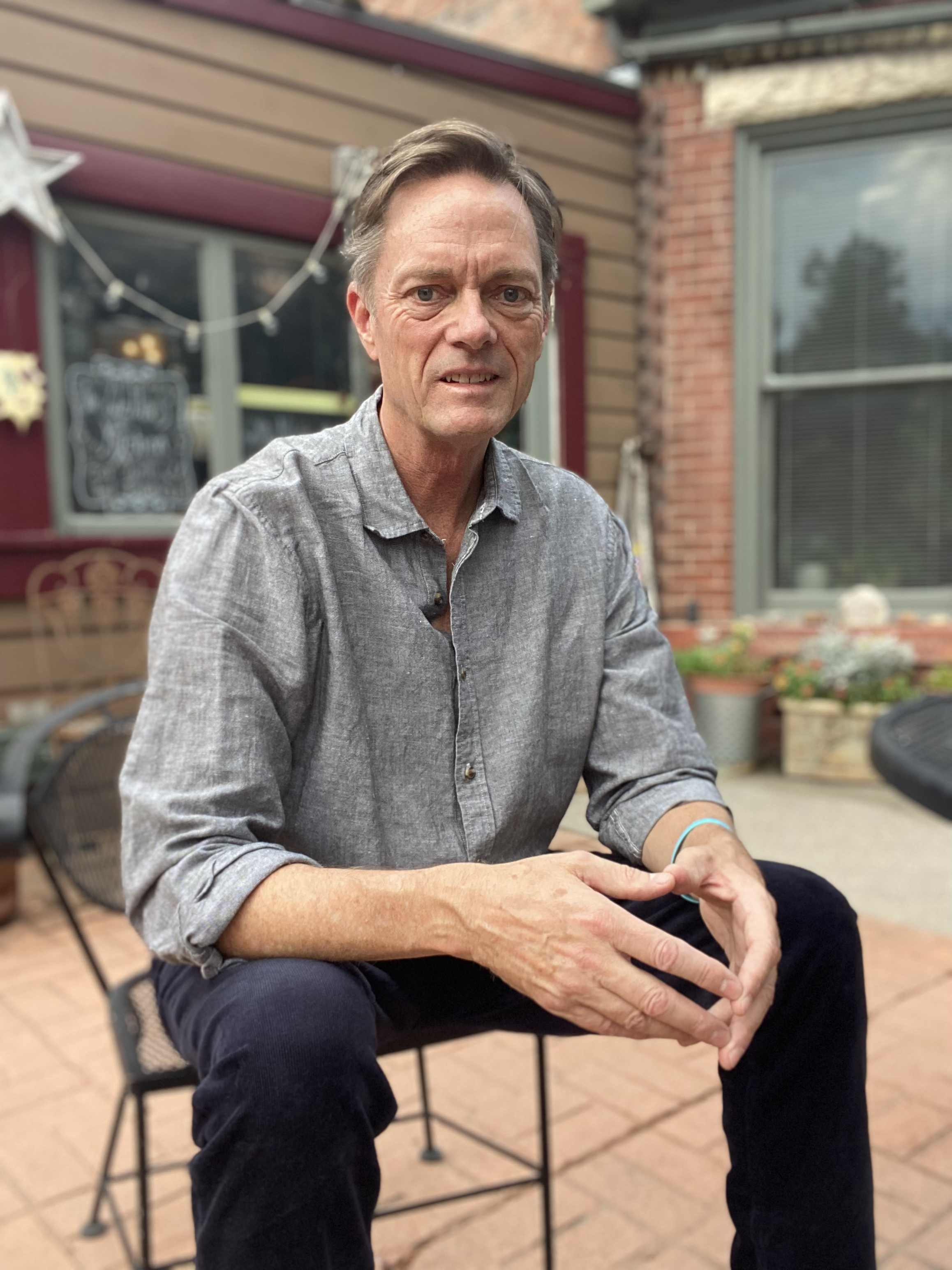 Man in a gray shirt sitting outside a storefront