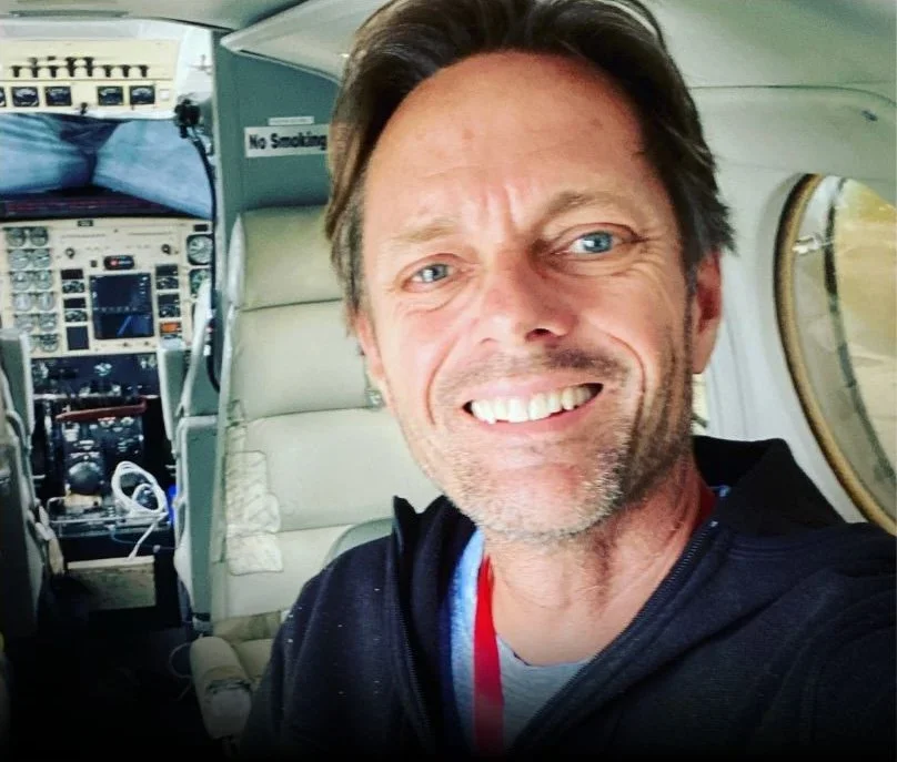 Smiling man taking a selfie inside a small aircraft next to the cockpit controls