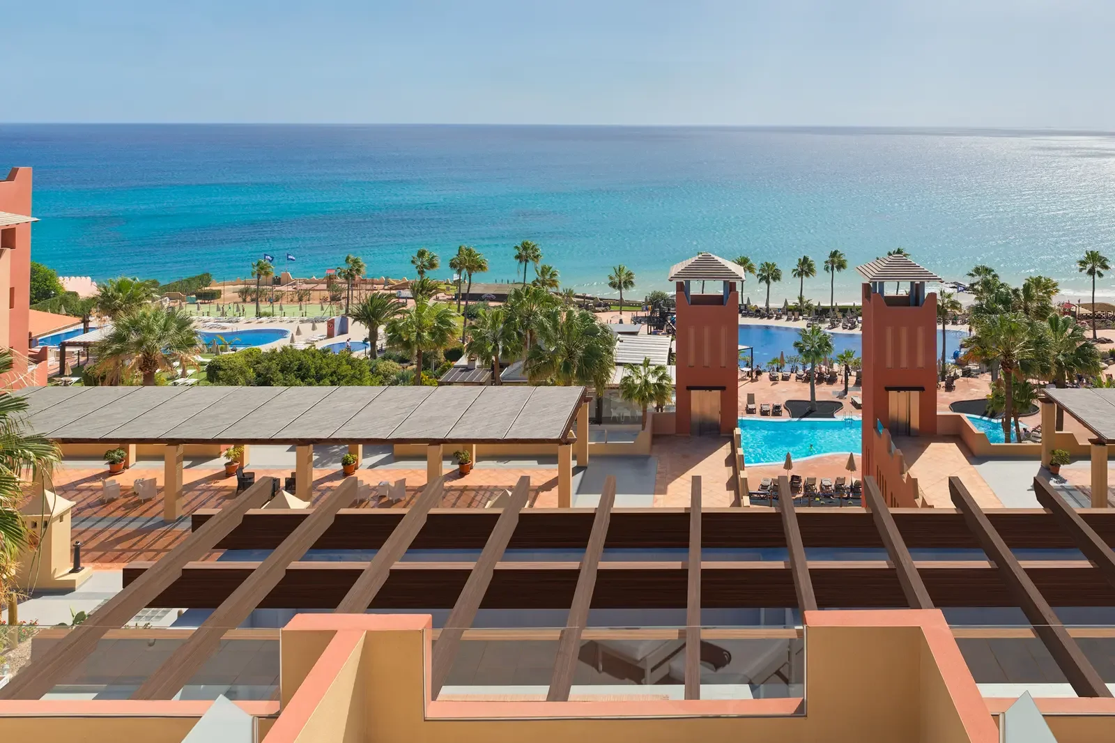 Uitzicht op een resort met zwembaden, palmbomen en uitzicht op de zee en de horizon.