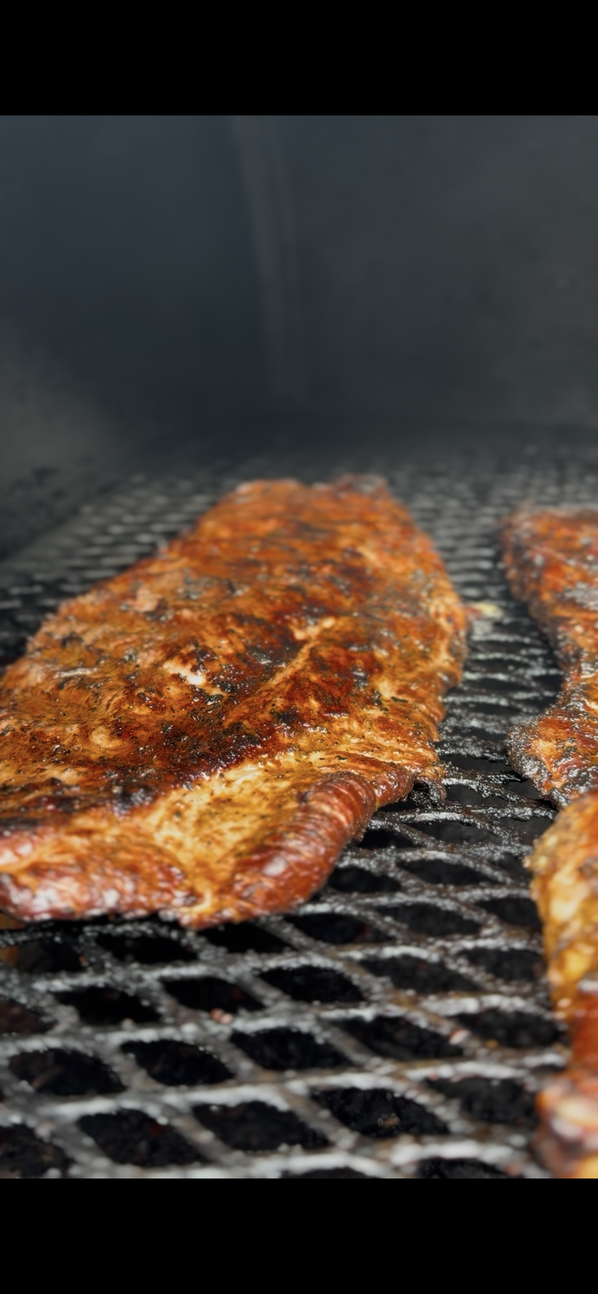 Close-up of seasoned meat grilling on a barbecue.