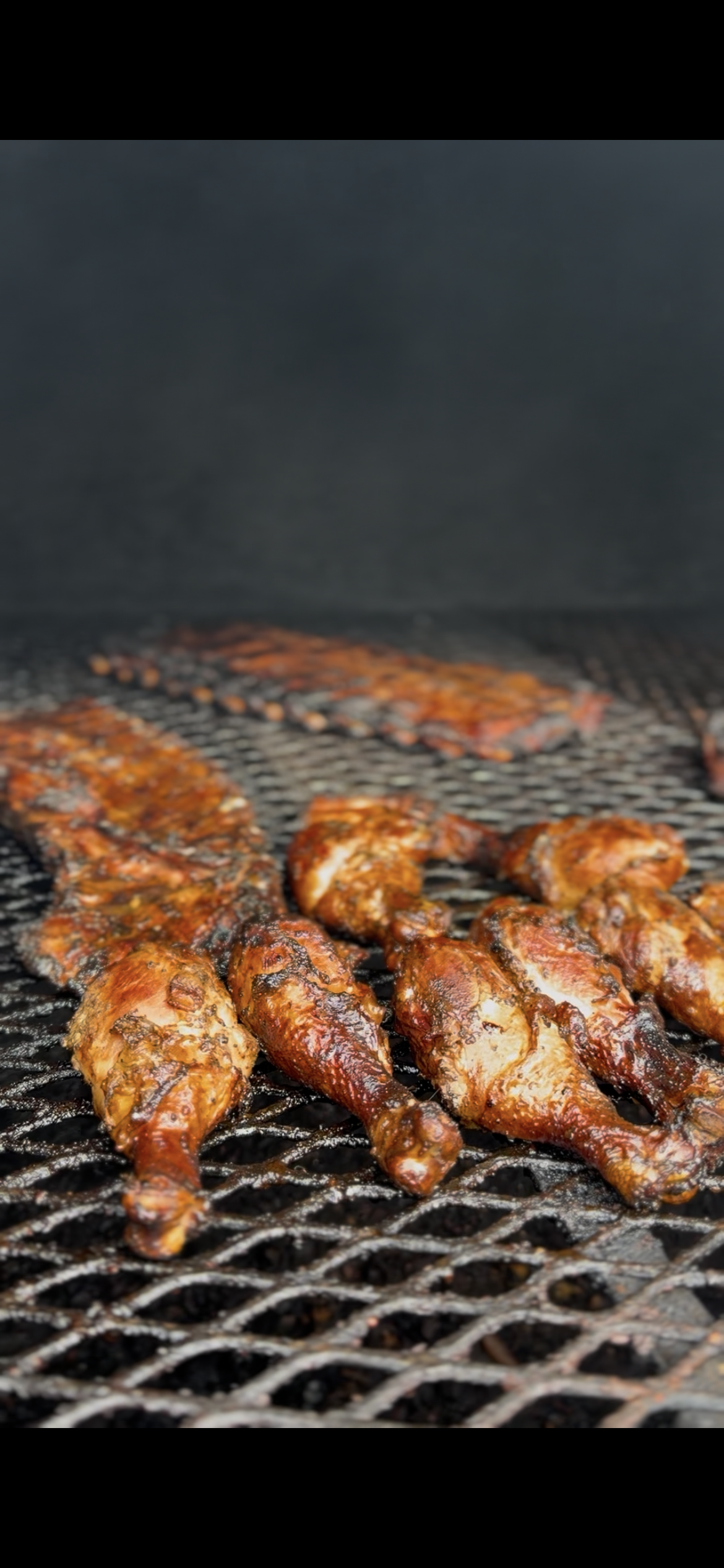 Chicken drumsticks grilling on a barbecue with a hot grill and visible flames.