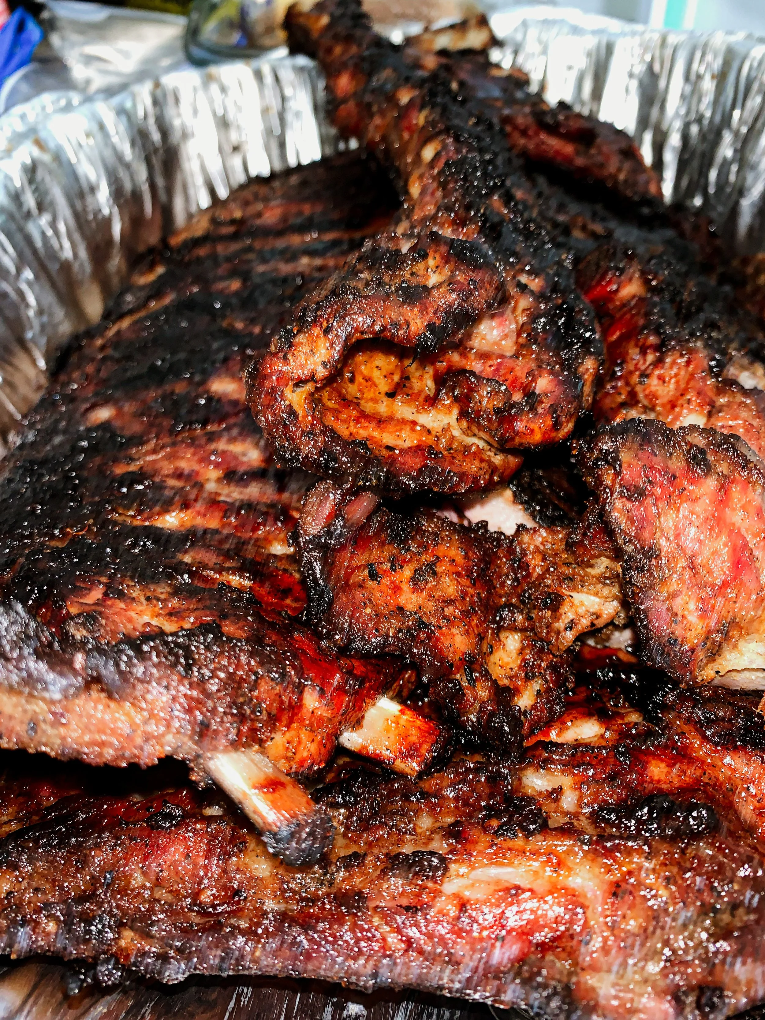 Close-up of grilled, roasted pork ribs with charred and caramelized exterior on a metal baking tray.