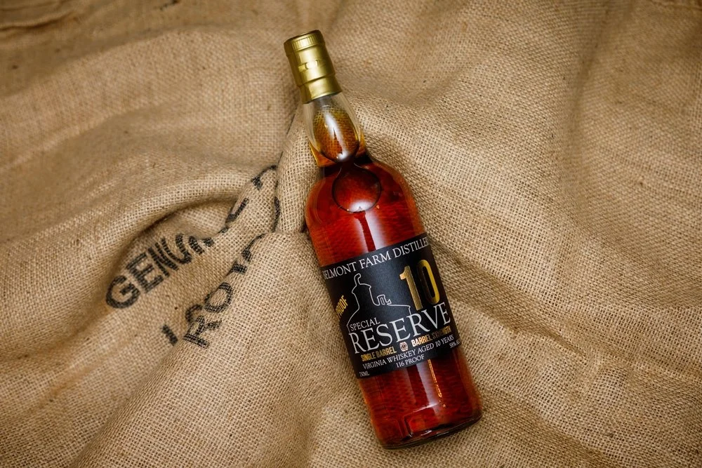 A bottle of Belmont Farm Distillery Reserve Special Reserve whiskey resting on a burlap sack.