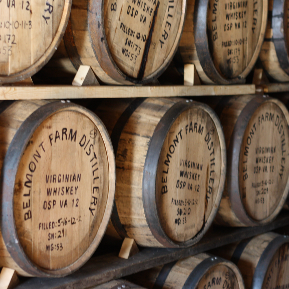 Stacked wooden barrels labeled "Bellemont Farm Distillery" containing Virginian whiskey.