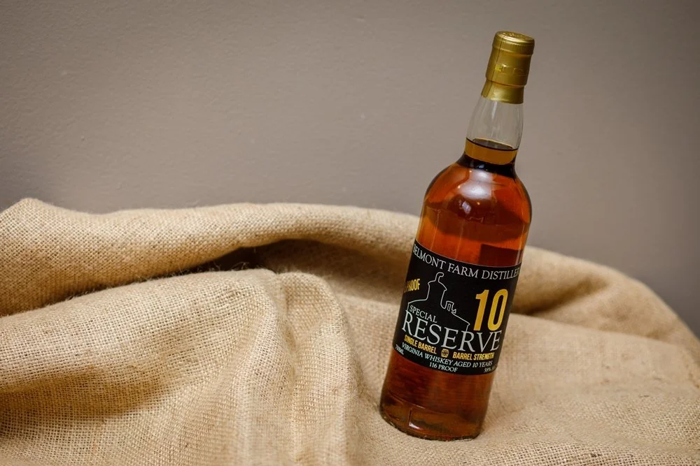A bottle of Belmont Farm Distillery Virginia whiskey, labeled 'Special Reserve 10', placed on a beige fabric surface.