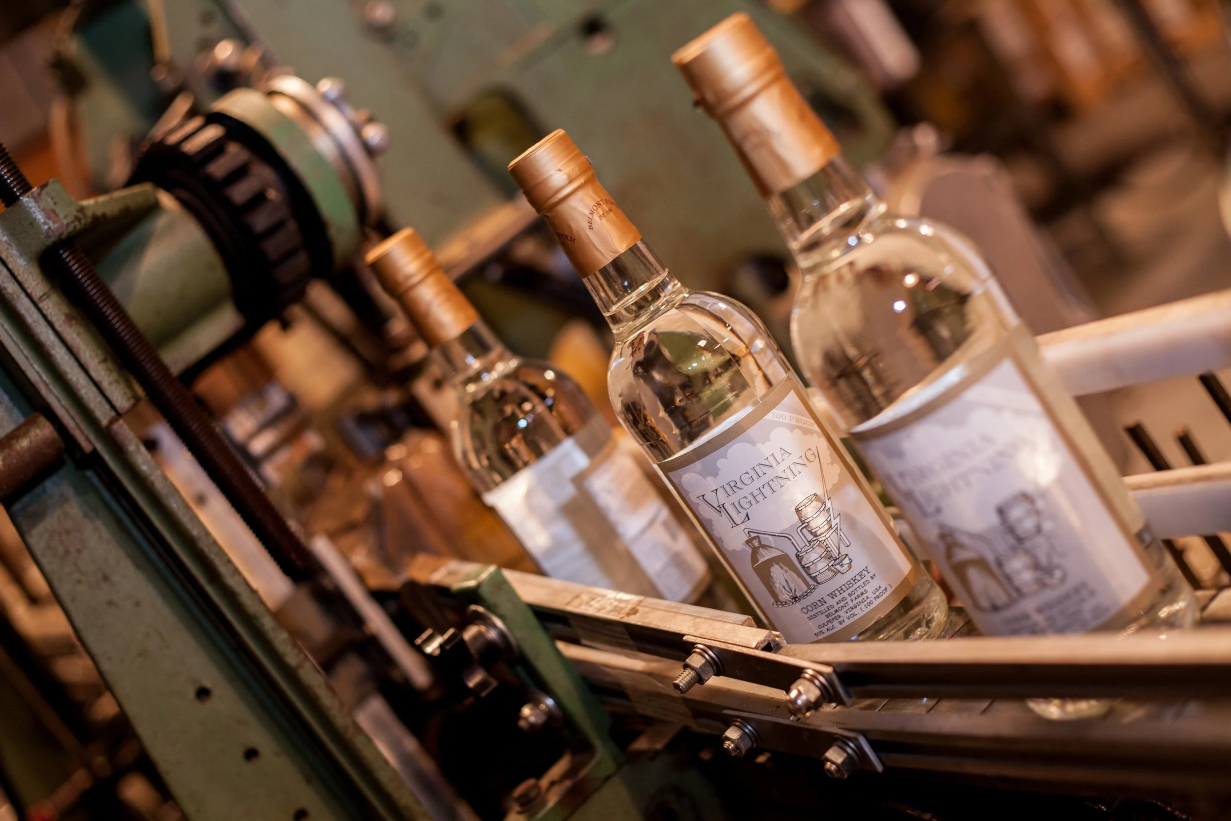 Glass bottles of whiskey in a distillation process on an industrial machine.