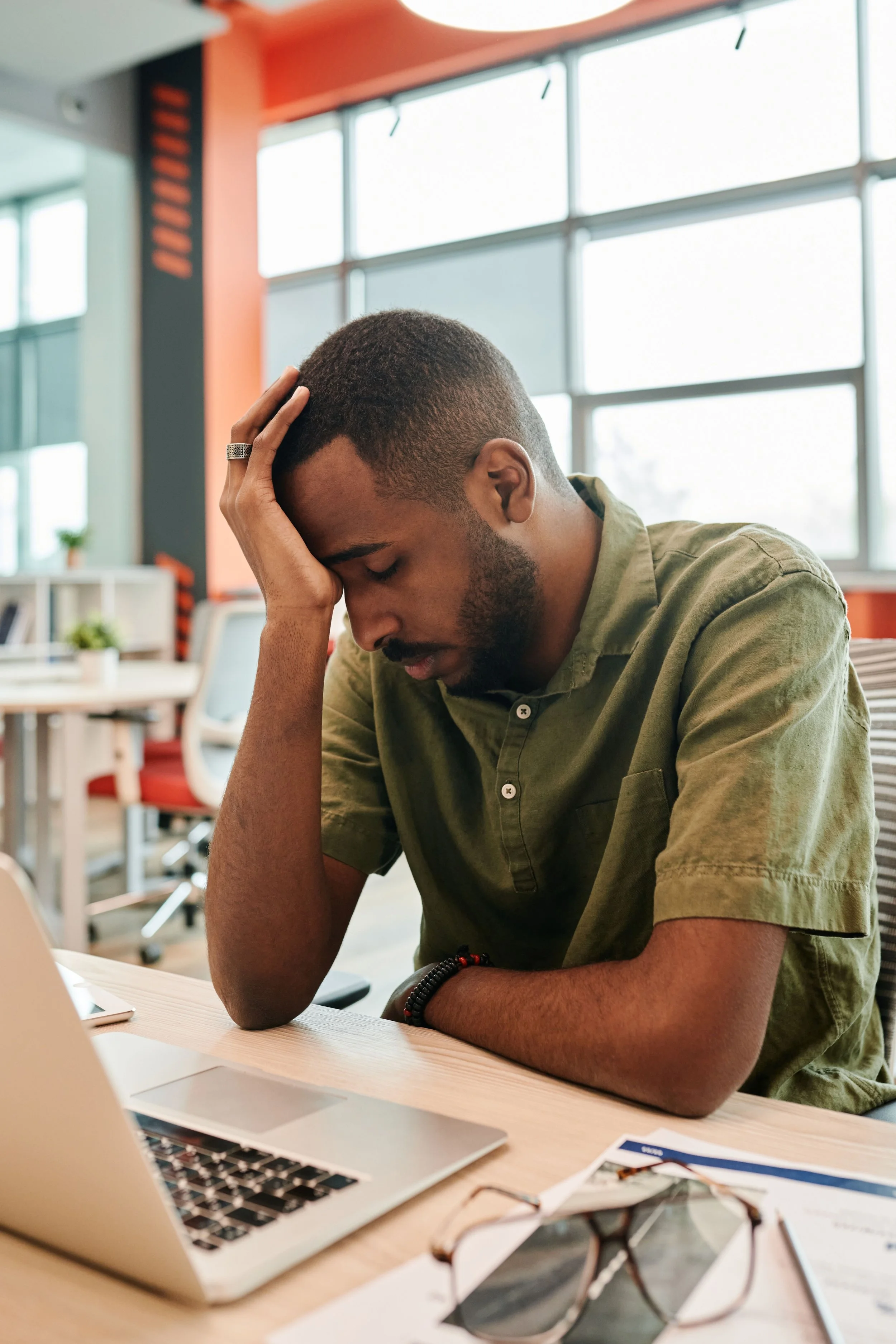 A man sitting at his desk looking overwhelmed while working in an office.
