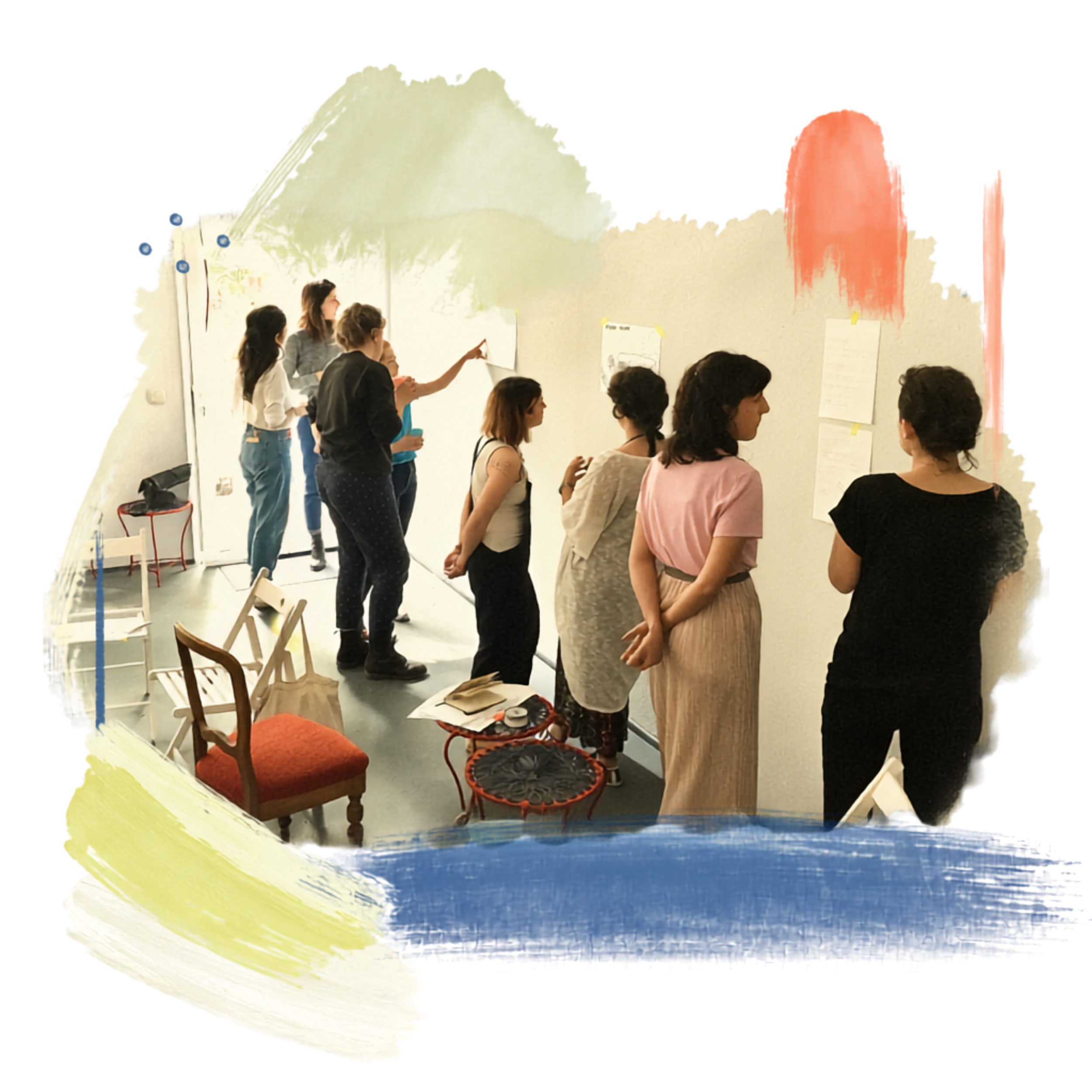 People gathered in a room with chairs and artwork on the wall, engaged in discussion or presentation.