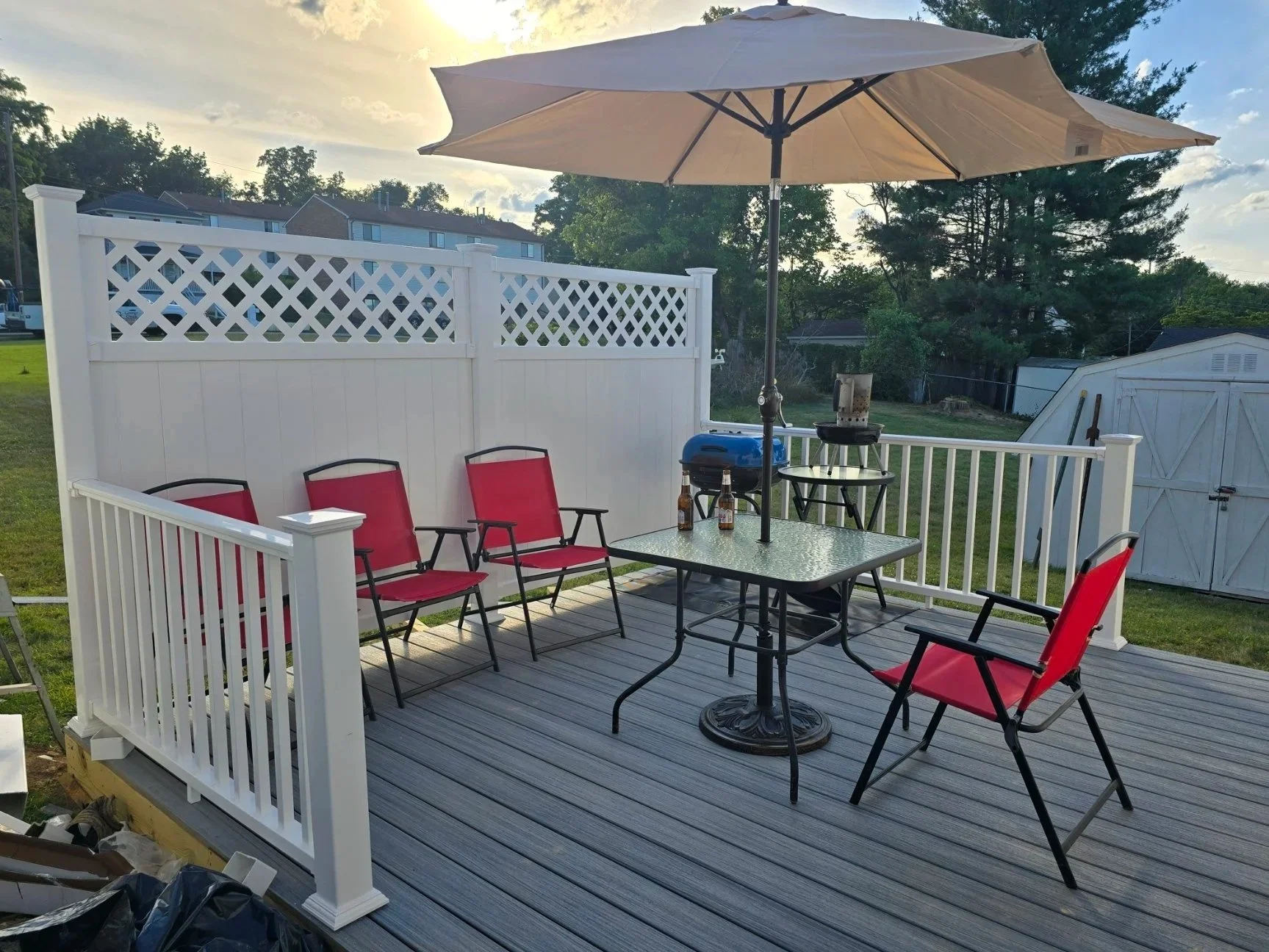 A recent complete deck with table. chairs , umbrella and charcoal grills