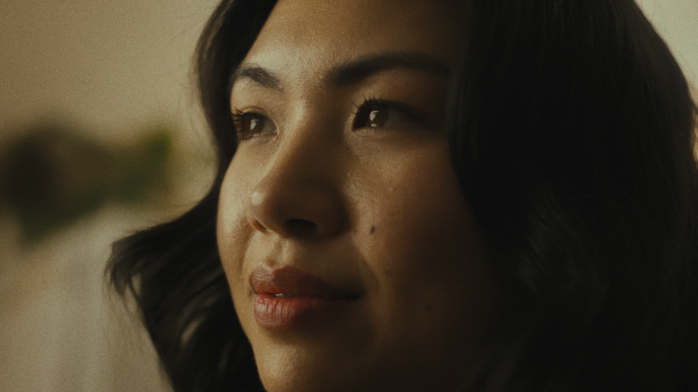 Close-up of a woman's face with dark hair, fair skin, and makeup.