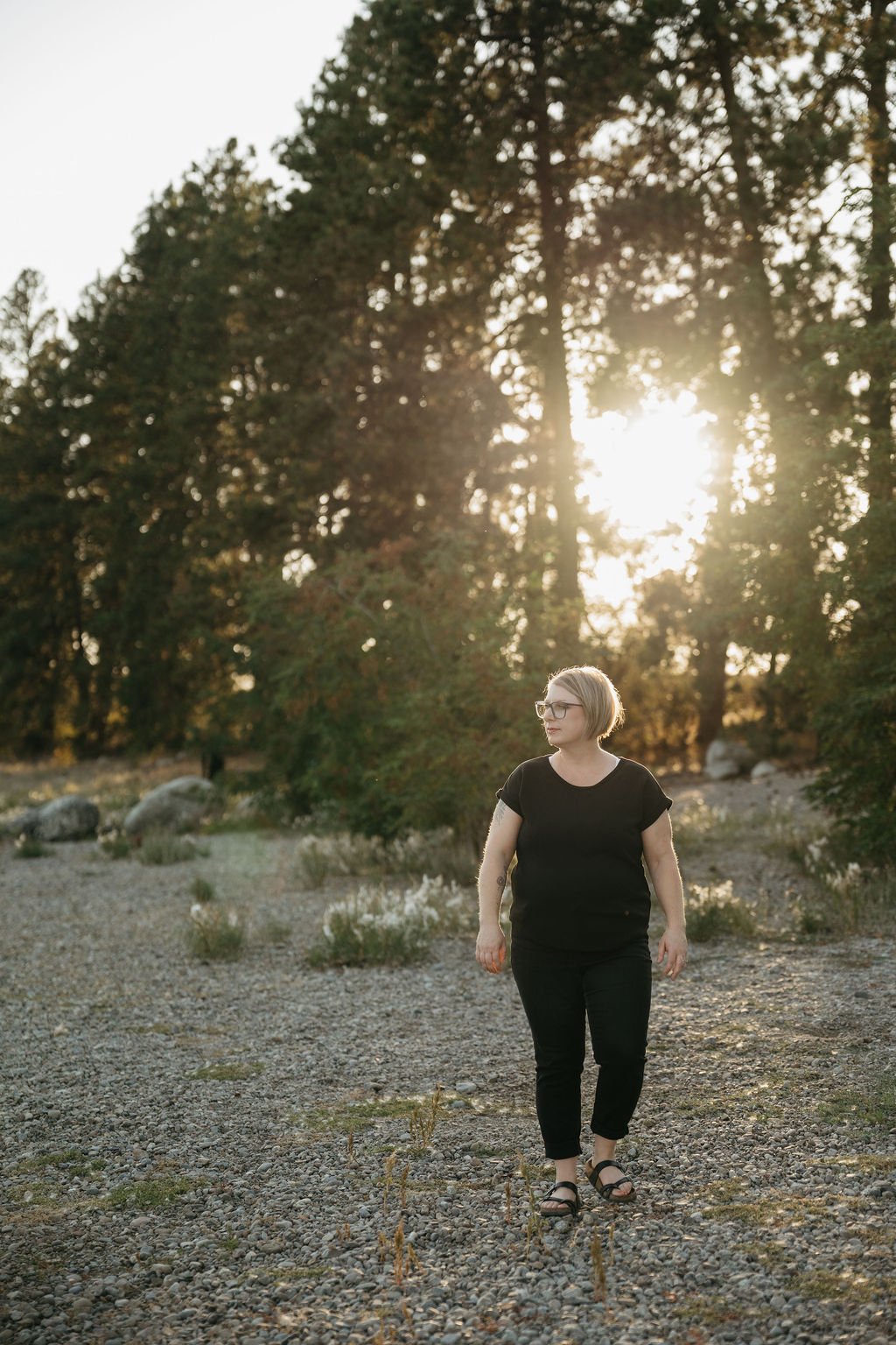 Woman looking off into the distance as the sun sets in the distance behind her.