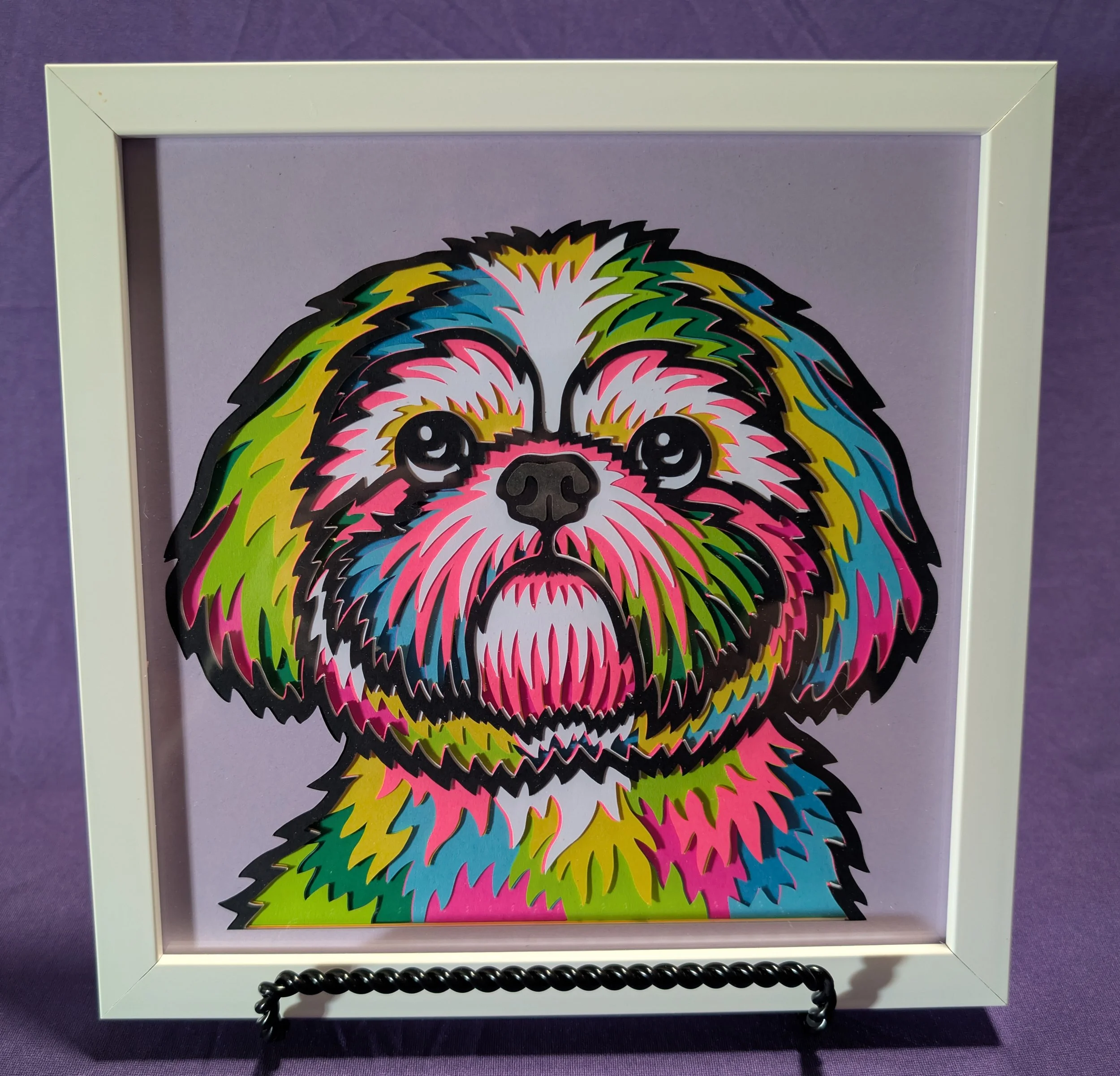Colorful sticker art of a dog's face with large eyes and vibrant rainbow-colored fur, framed in a white box with a purple background.