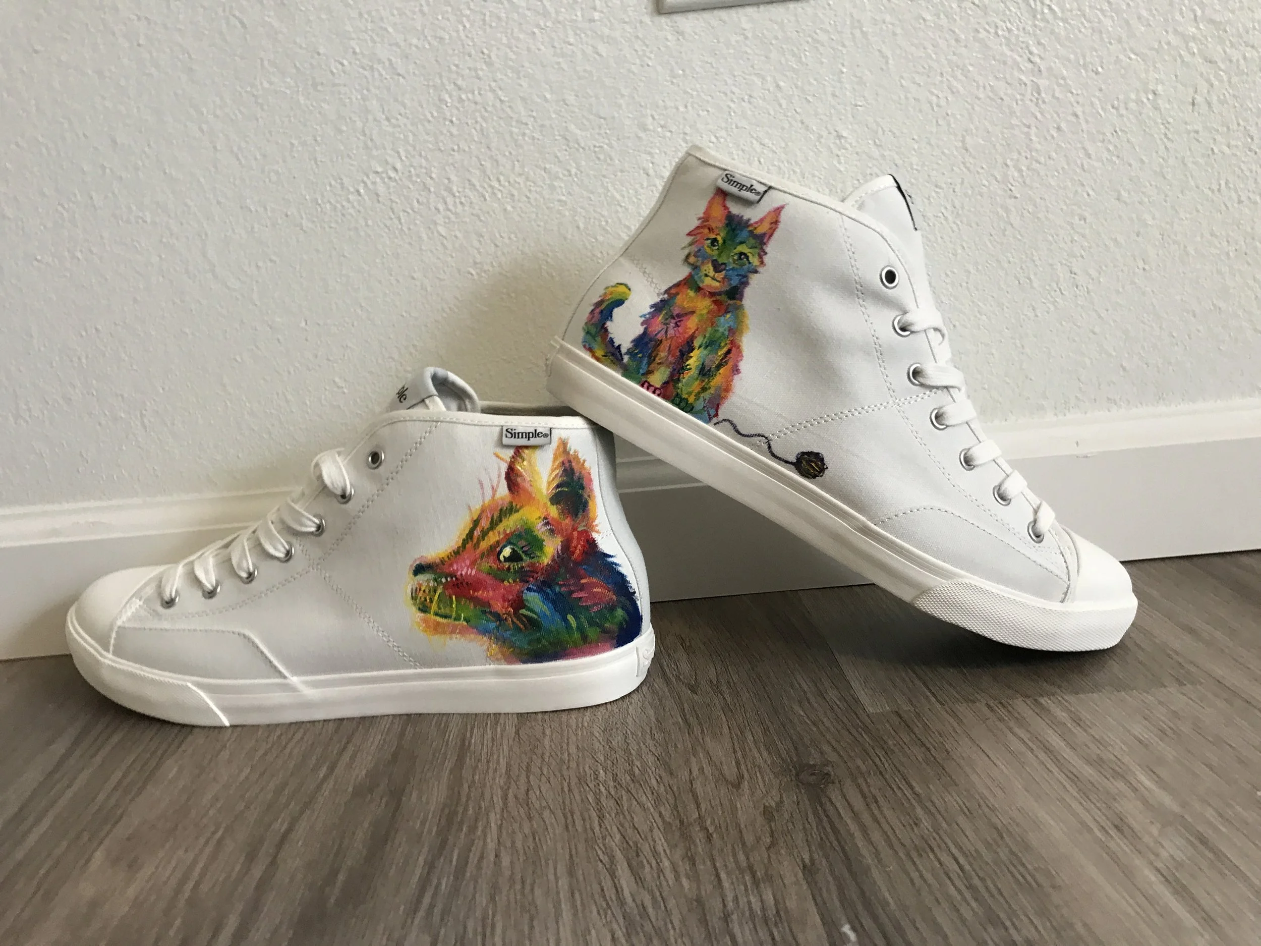 White high-top sneakers with a colorful, rainbow-style cat design on the sides, hand painted. 