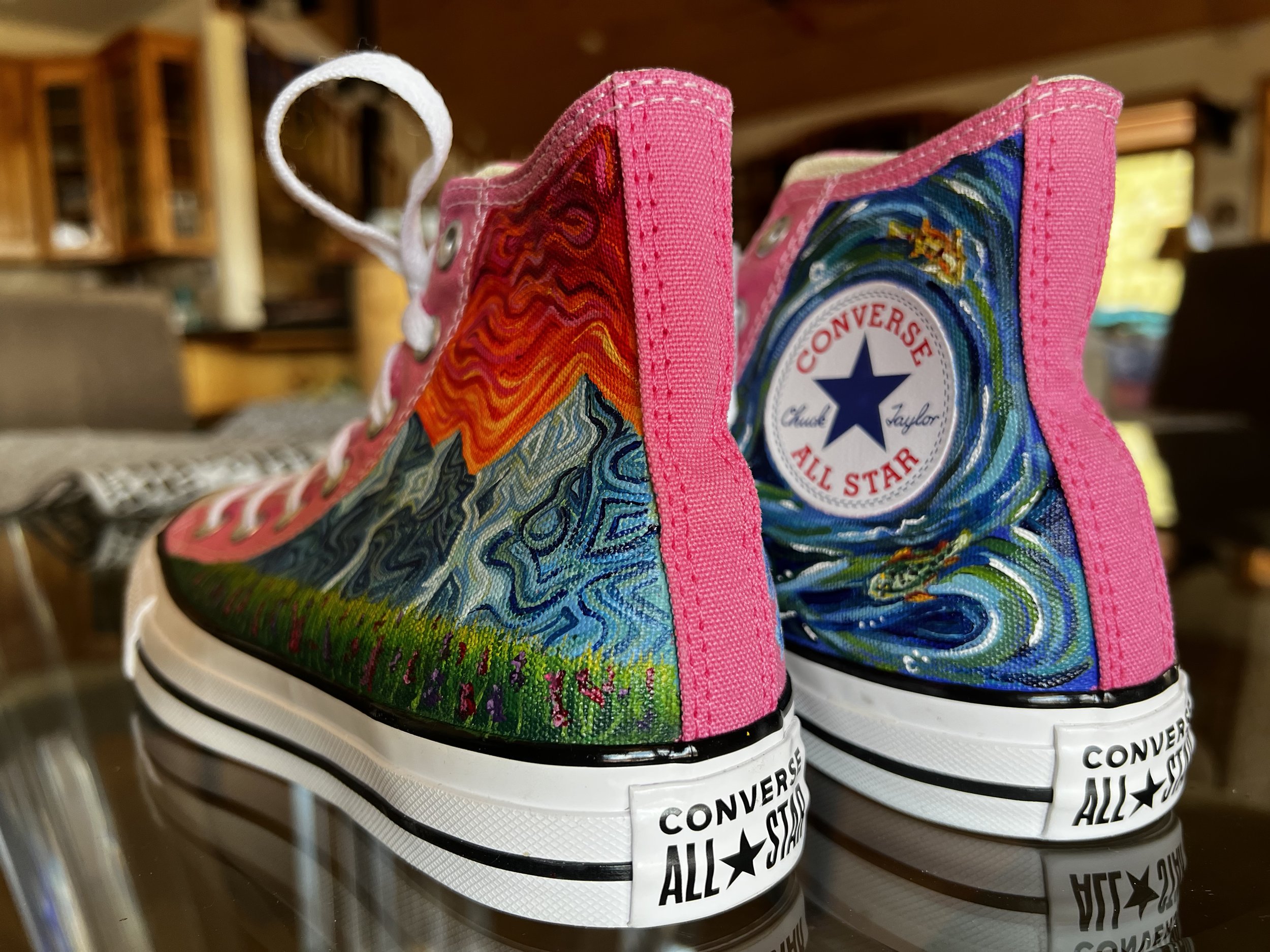 Close-up of colorful Converse All Star sneakers with hand painted mountains and trout in a river.