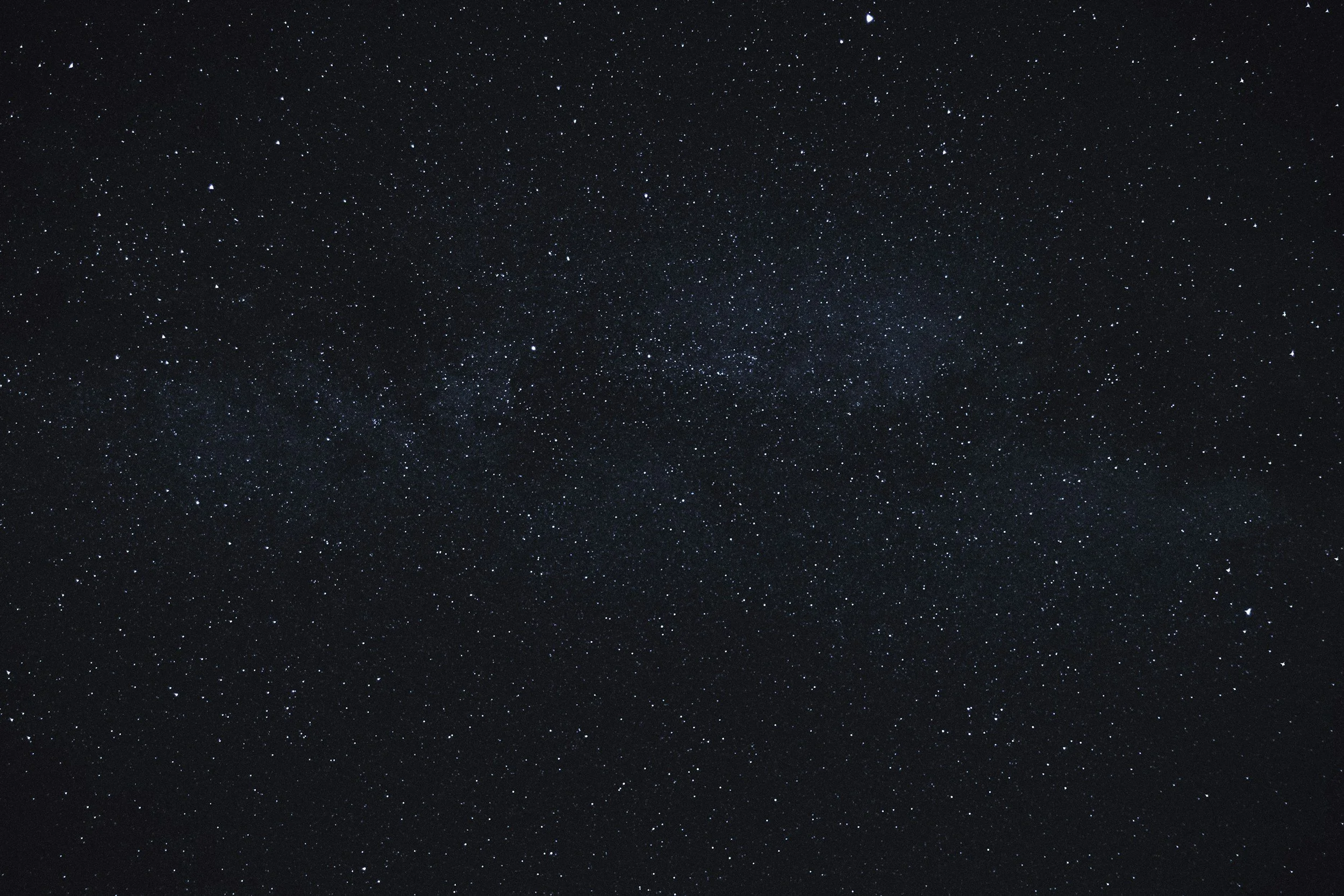 black sky with bright and distant stars and a light blue galaxy