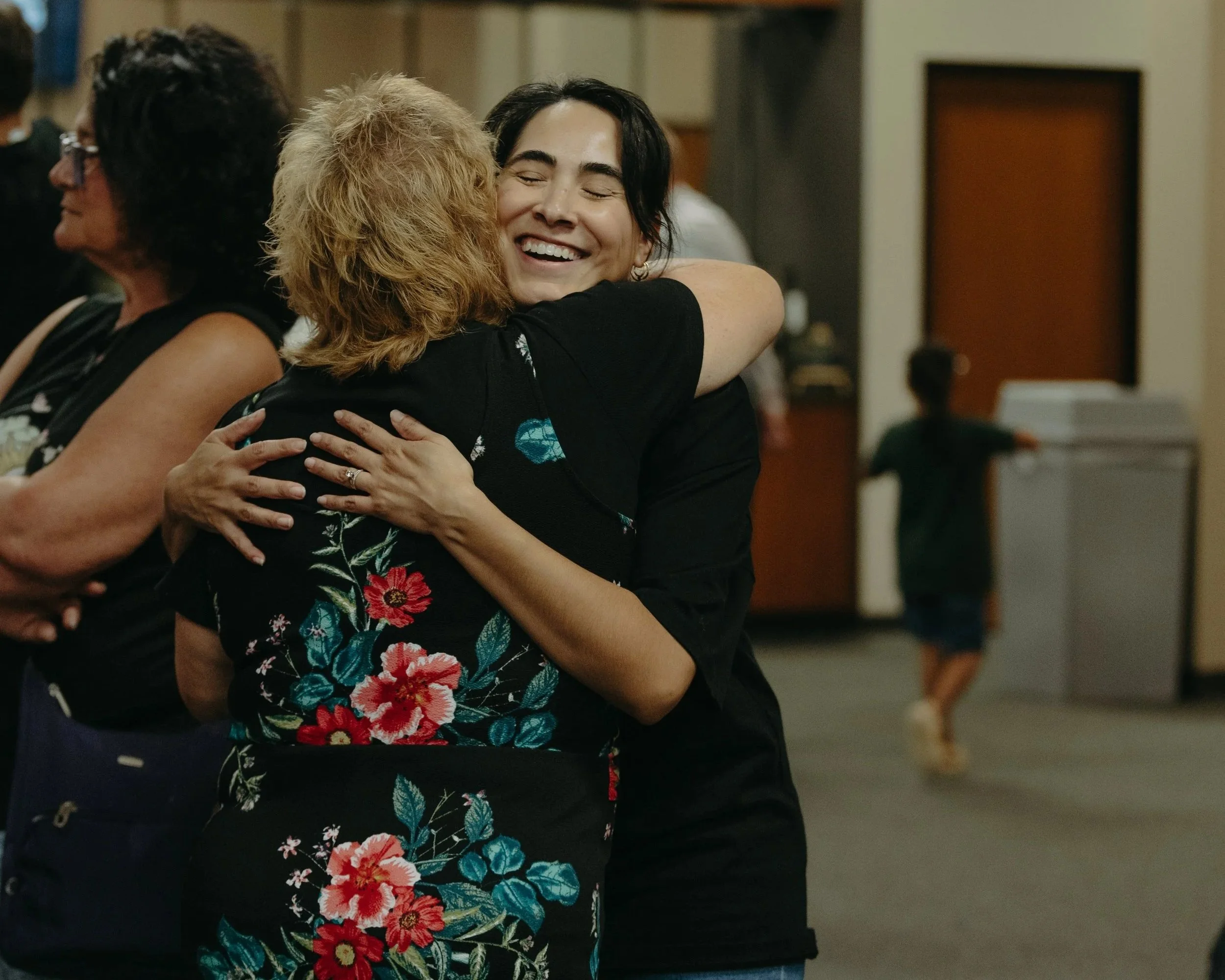 Two women hugging each other, smiling and enjoying a moment together.
