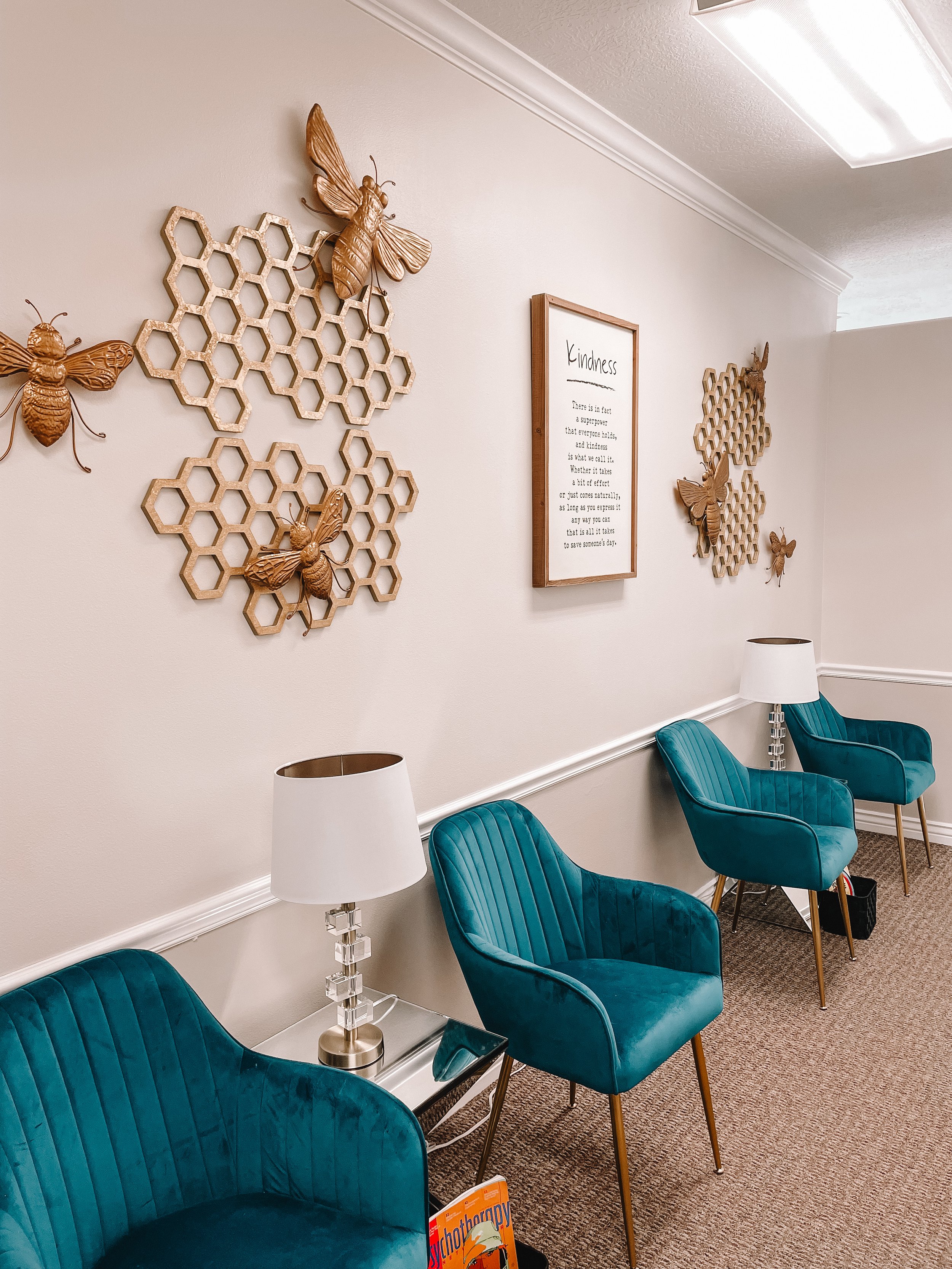 Waiting area with teal chairs and bee-themed honeycomb wall art at Blue Bee Counseling
