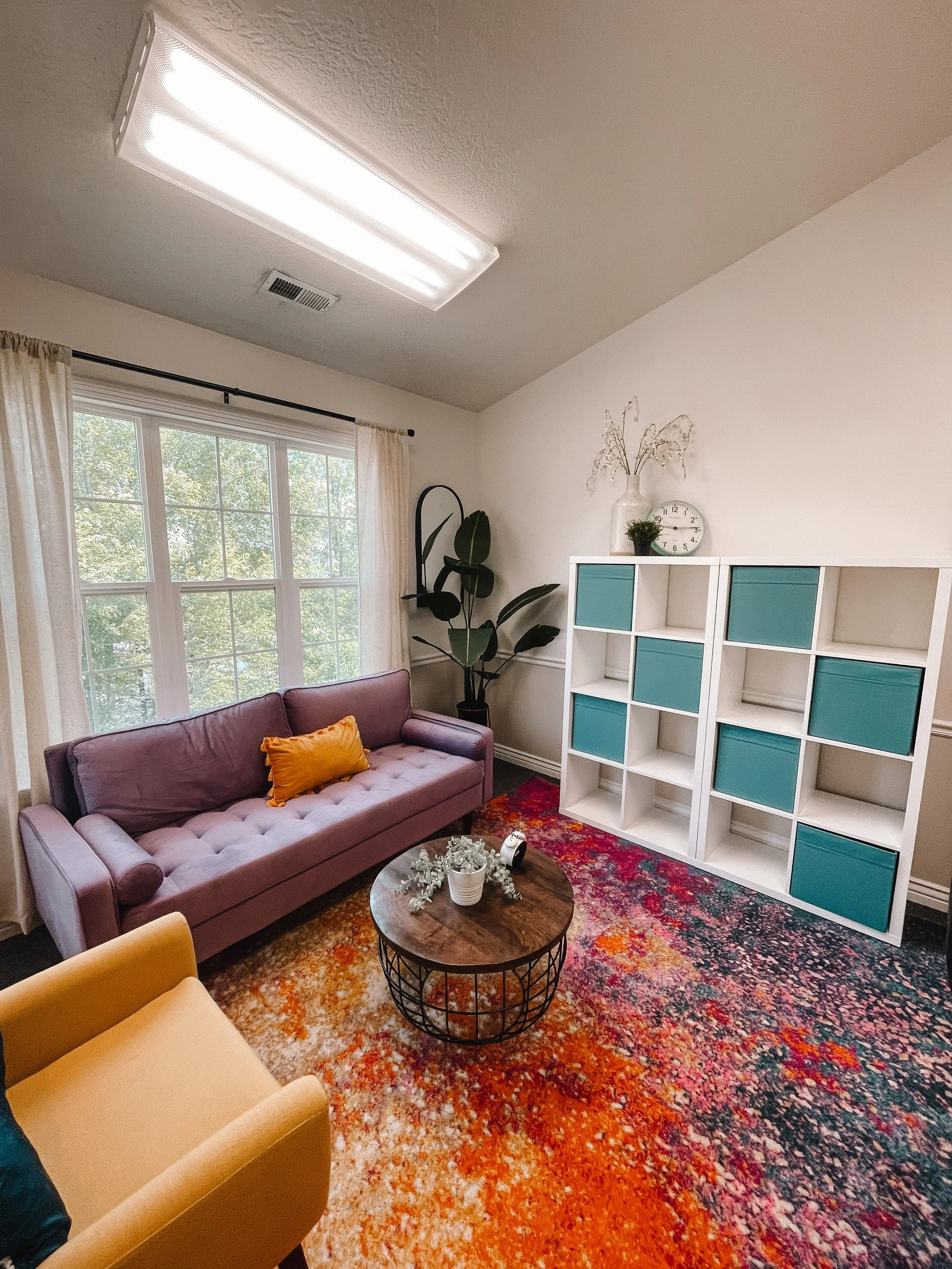 Therapy office in south jordan with colorful rug, purple couch, and natural lighting