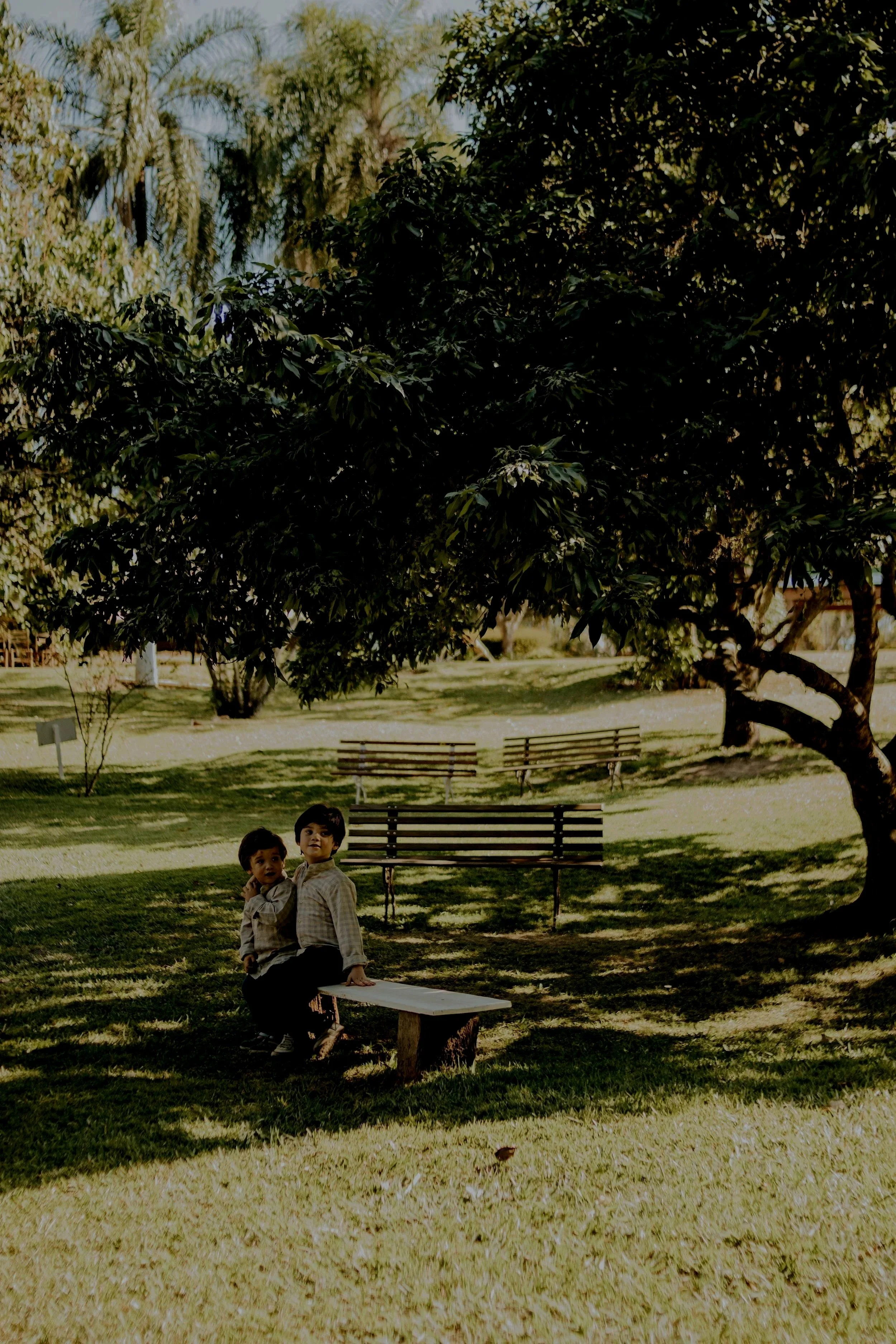two children sitting on a bench outside