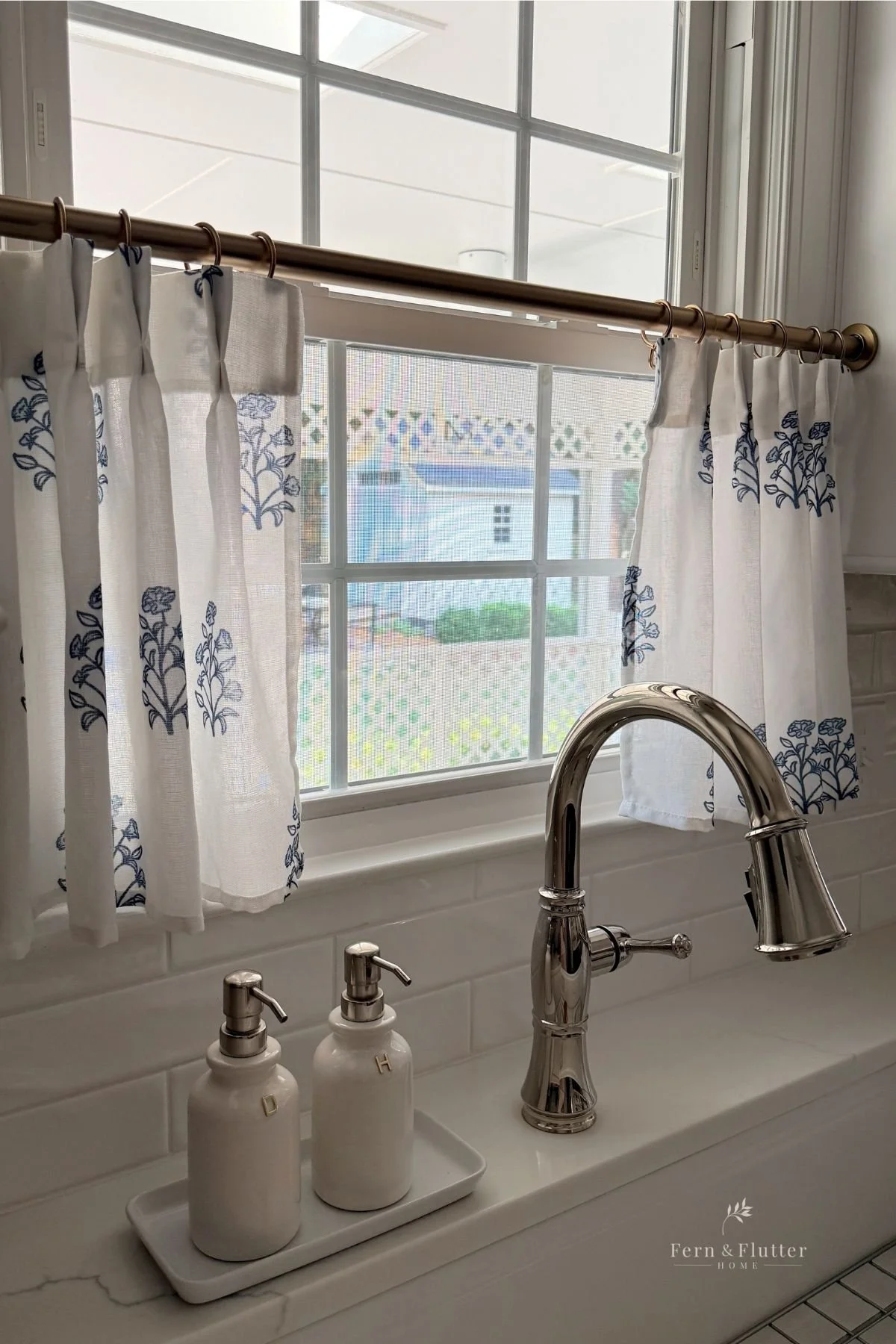 Affordable blue block print café curtains on a brass rod with rings.