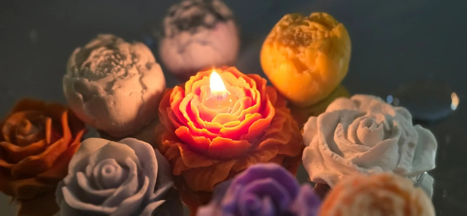 Decorative candles in the shape of roses, with one candle lit in the center