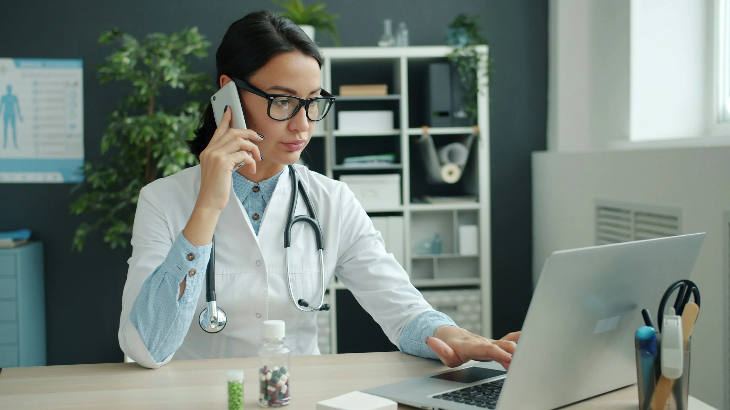 Physician in white coat with stethoscope reviewing patient information