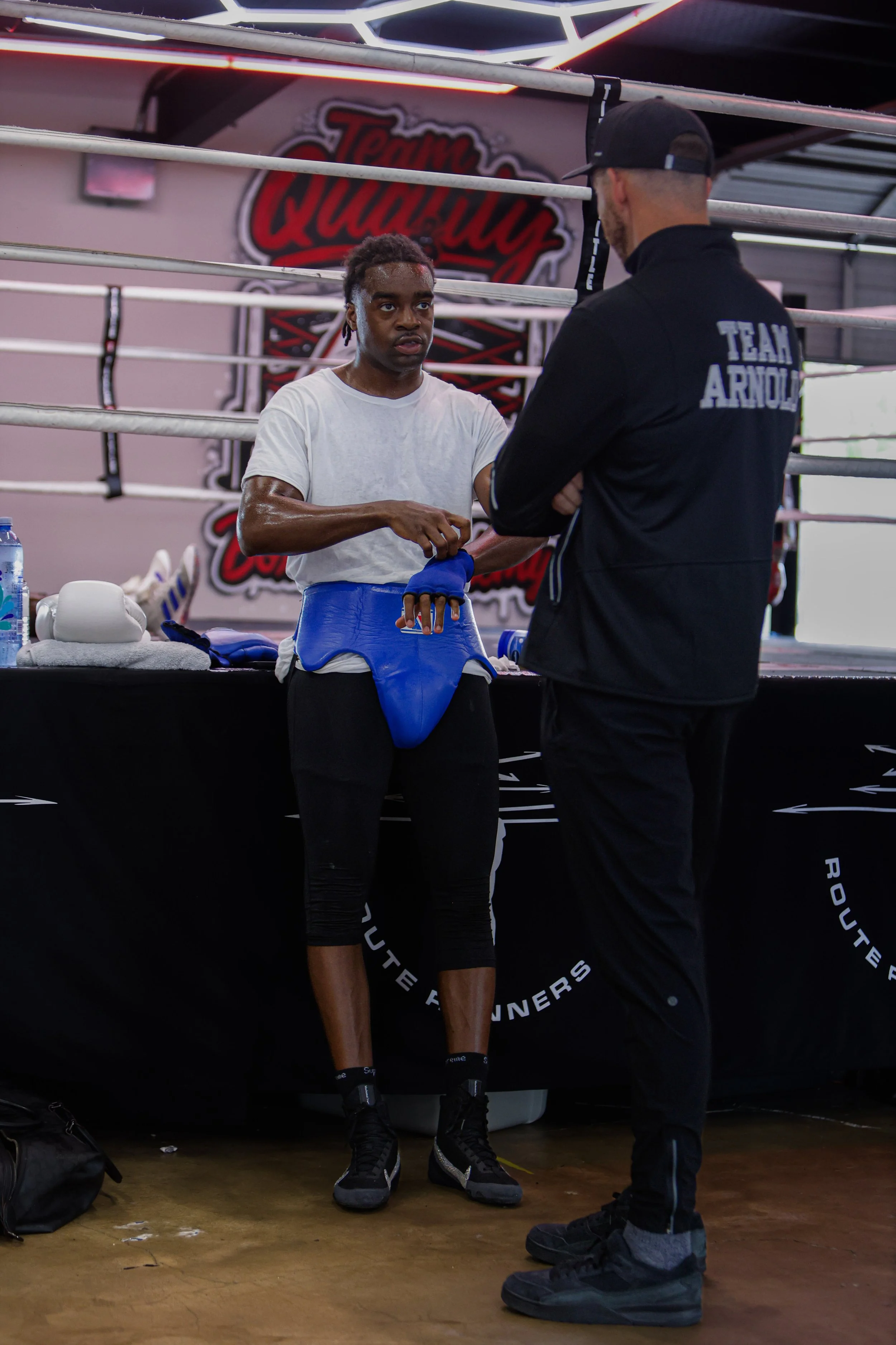 Samuel "S3" Arnold III exchanging conversation with Coach Andrew Banner in the boxing gym during fight camp preparation.