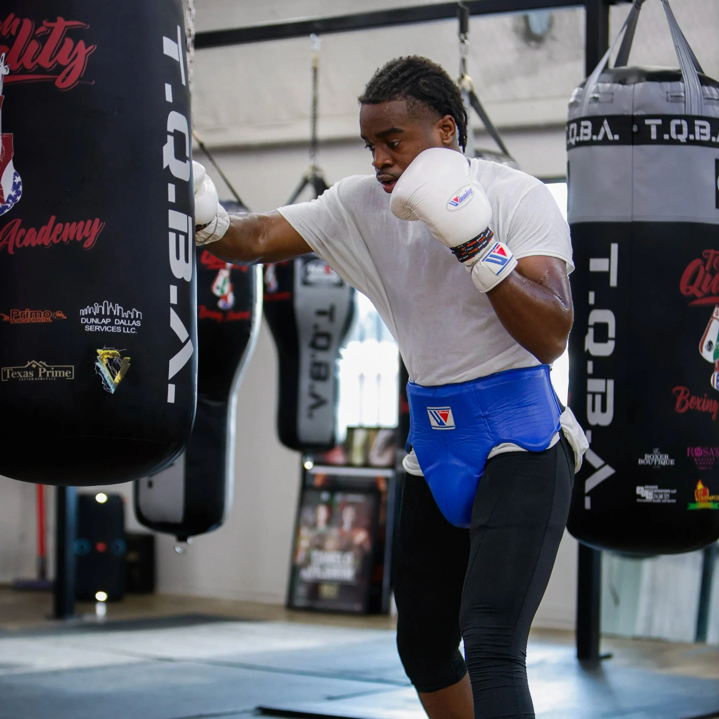 Samuel "S3" Arnold III training on the punching bag in white gloves.