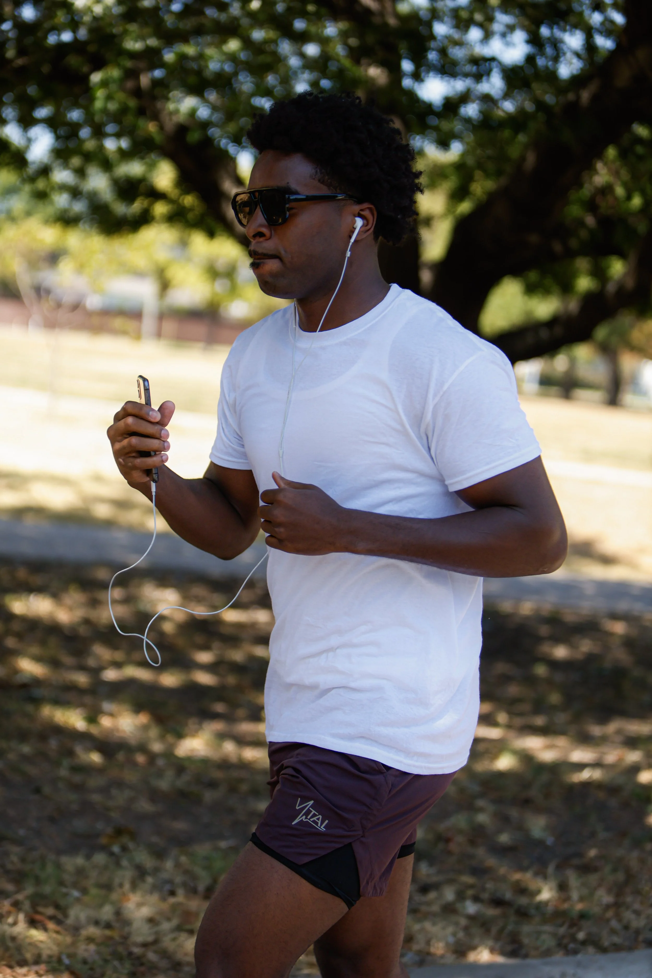 Samuel "S3" Arnold III doing outdoor roadwork during fight camp, running in a white t-shirt and headphones ahead of his October 10 Champions of Tomorrow bout.