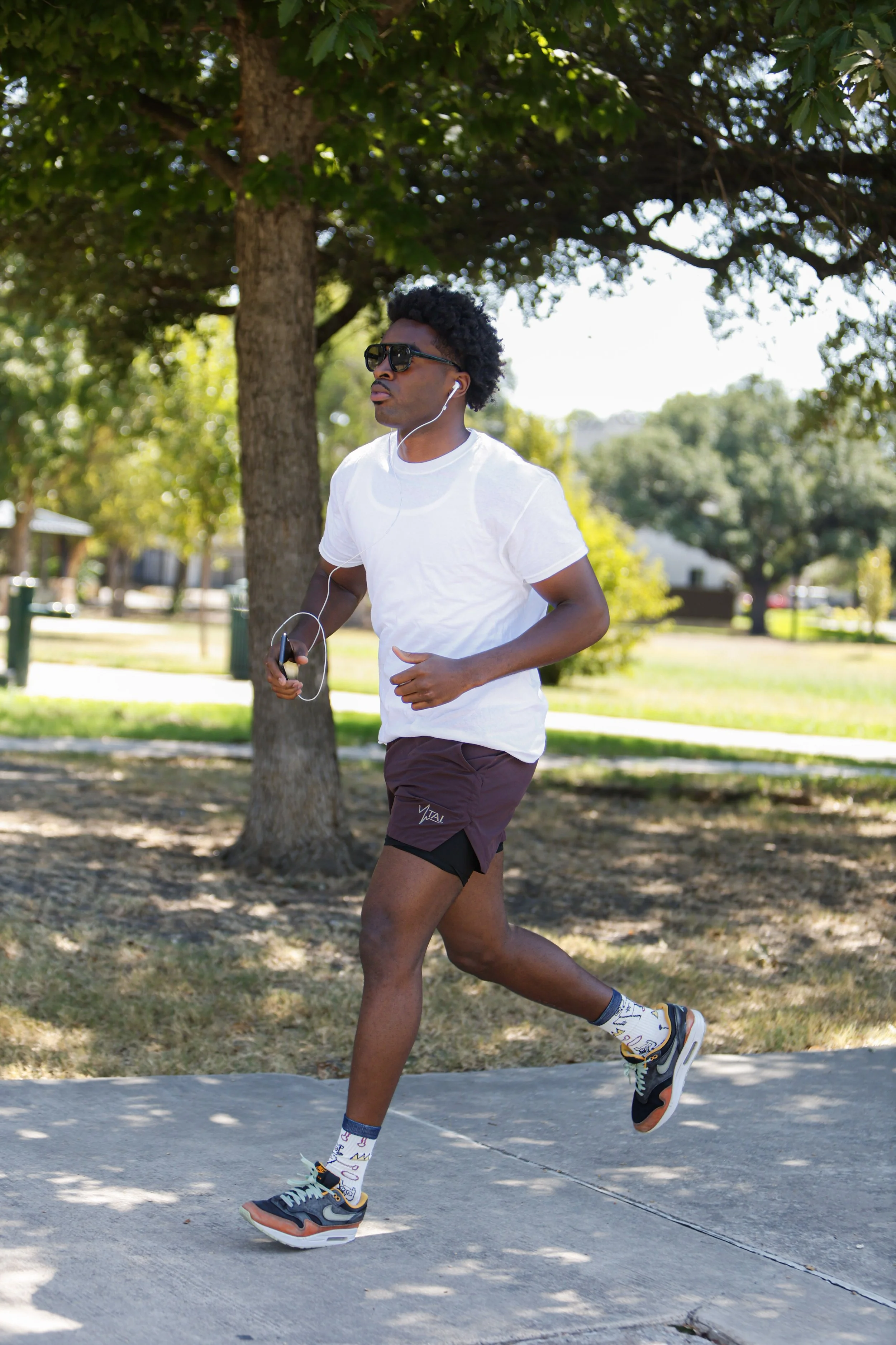 Samuel "S3" Arnold III doing outdoor roadwork during fight camp, running in a white t-shirt and headphones ahead of his October 10 Champions of Tomorrow bout.