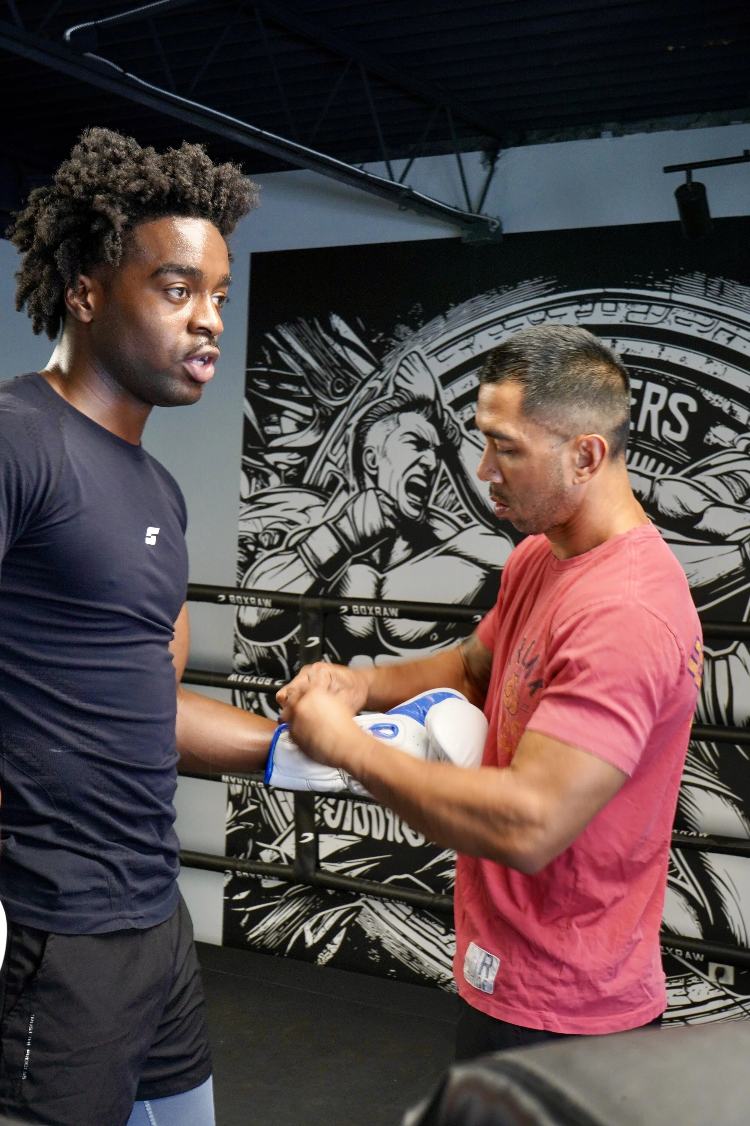 Samuel "S3" Arnold III and trainer John Pruna are putting on Sam's gloves at Strikers Gym in Dallas, Texas.
