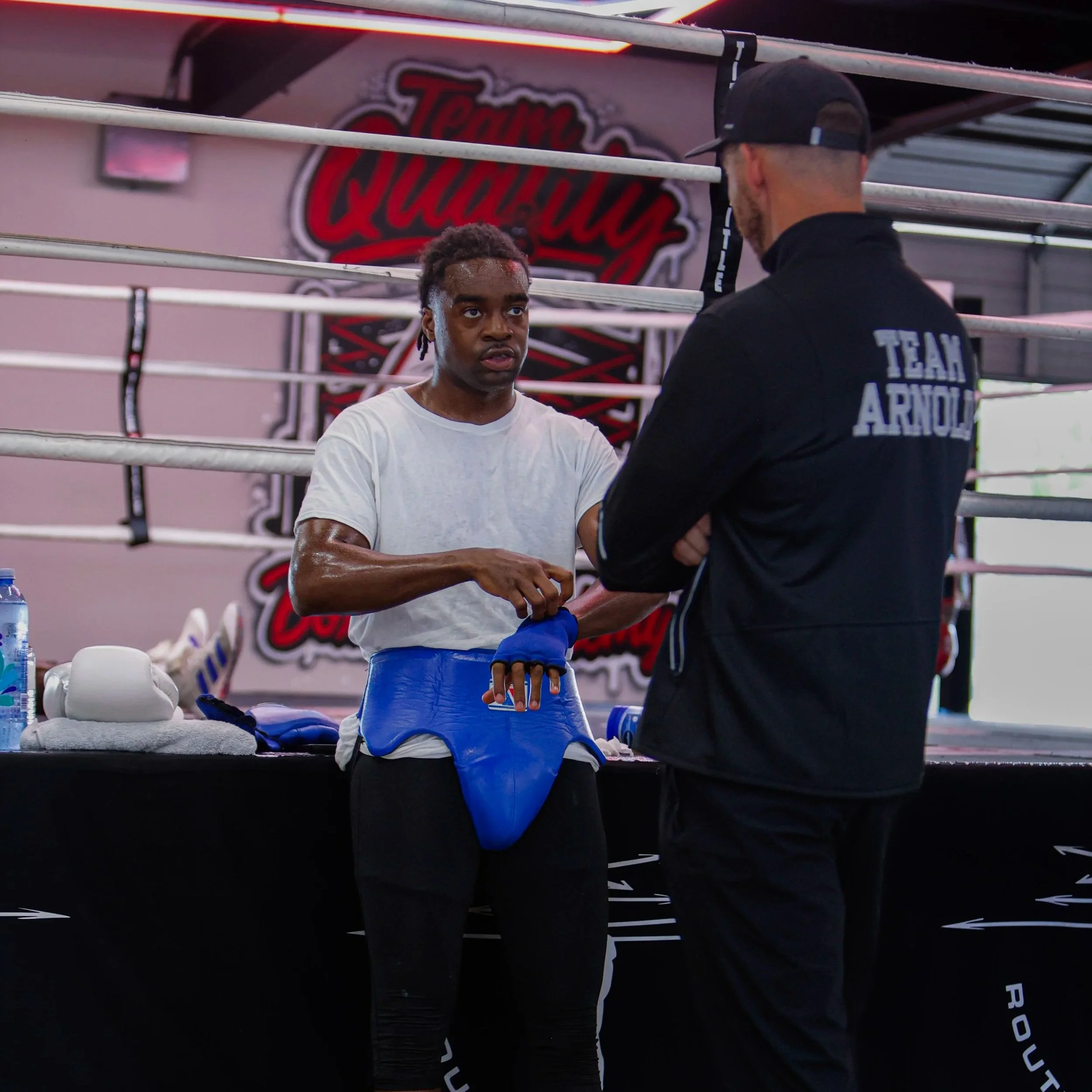 Samuel "S3" Arnold III exchanging conversation with Coach Andrew Banner in the boxing gym during fight camp preparation.