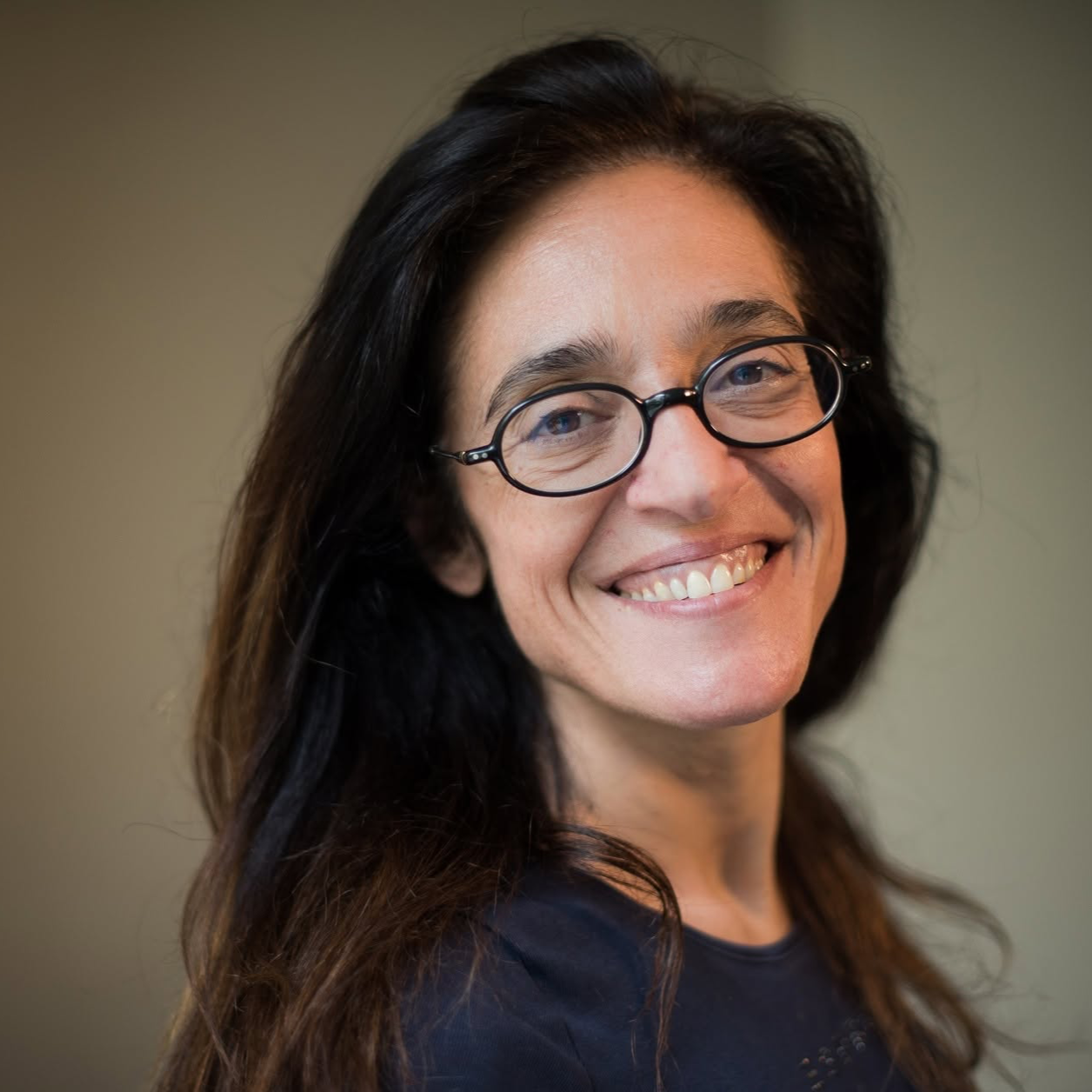 A smiling woman with long brown hair and glasses.