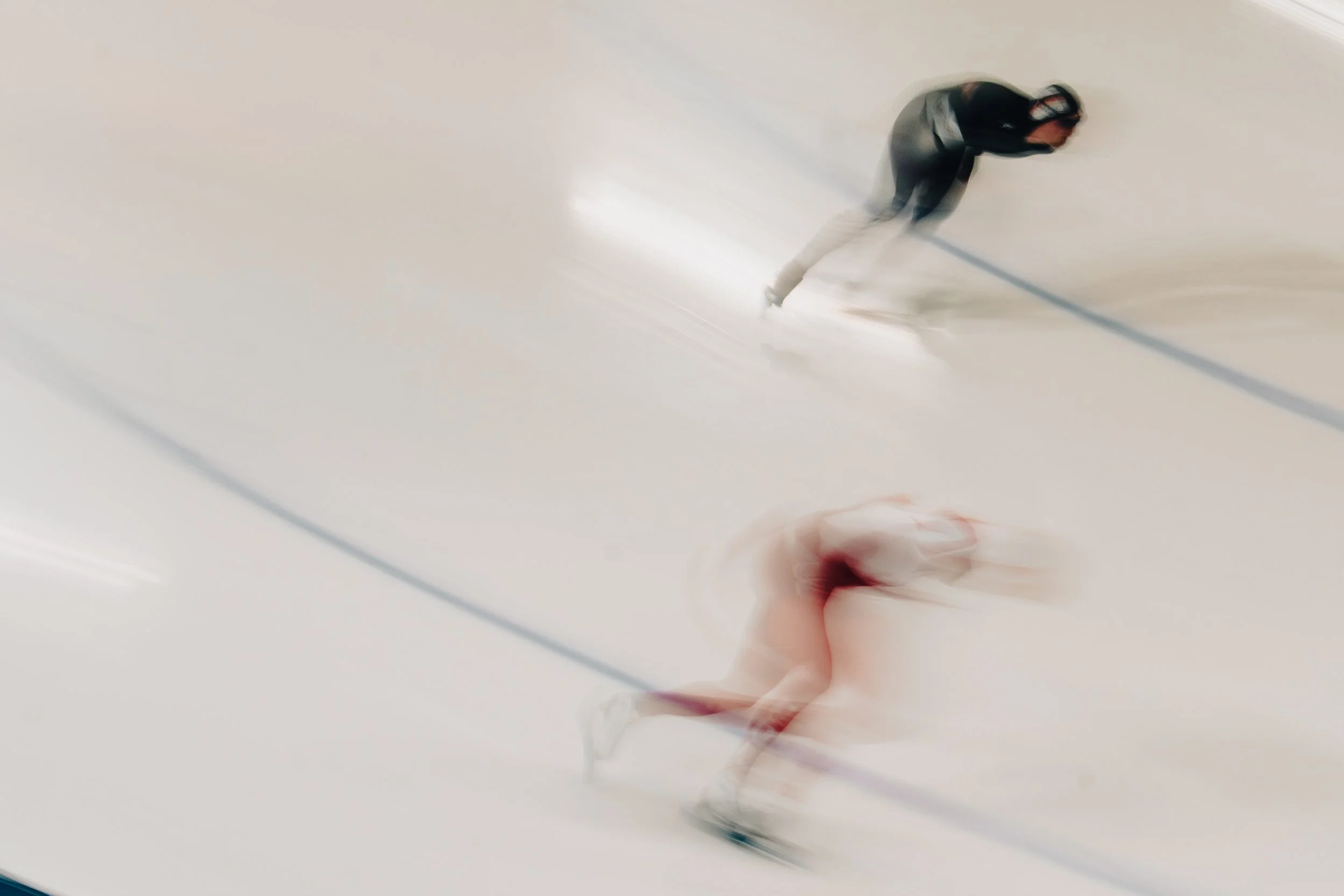 A person in black clothing and a hat is skating inside a white skating rink.