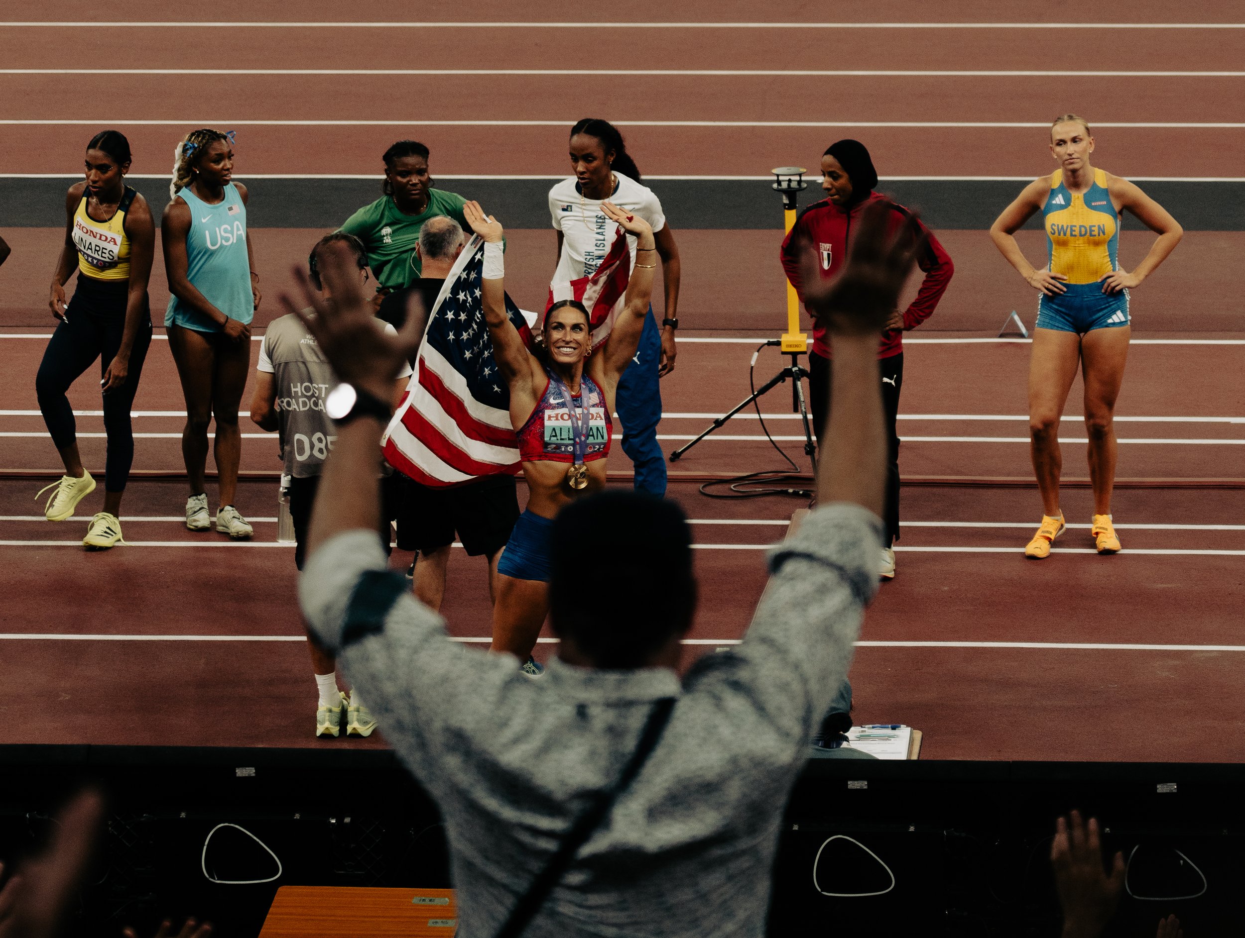 Female athletes and officials gathering on a track for a medal ceremony at a track event.
