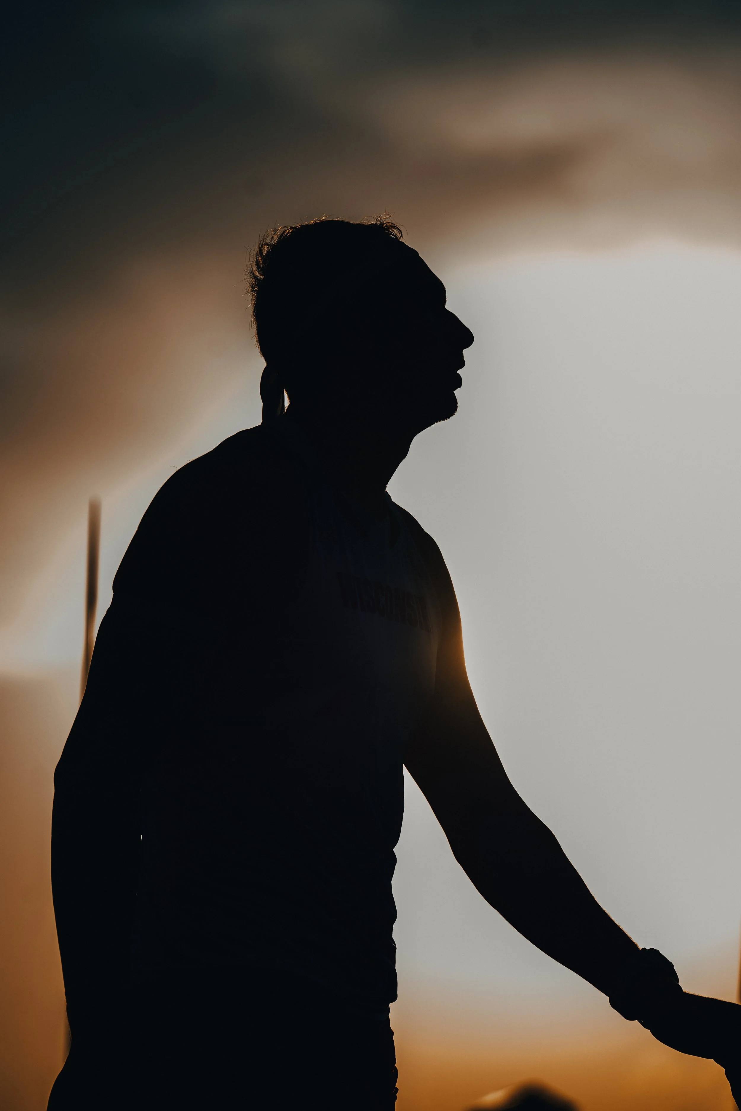 Silhouette of a person riding a bicycle during sunset or sunrise with a dark sky and horizon in the background.