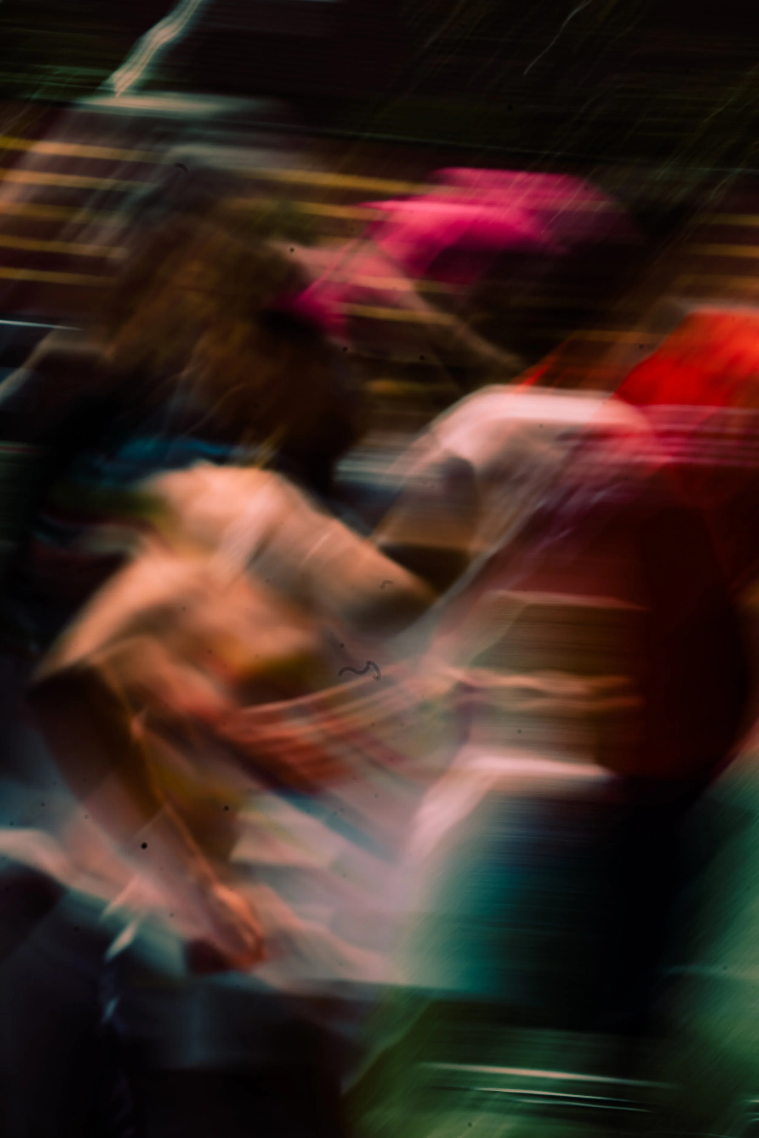 Abstract photo with blurred lights and colors, including pink, red, brown, black, and hints of blue and green, creating a dynamic, motion-filled effect.
